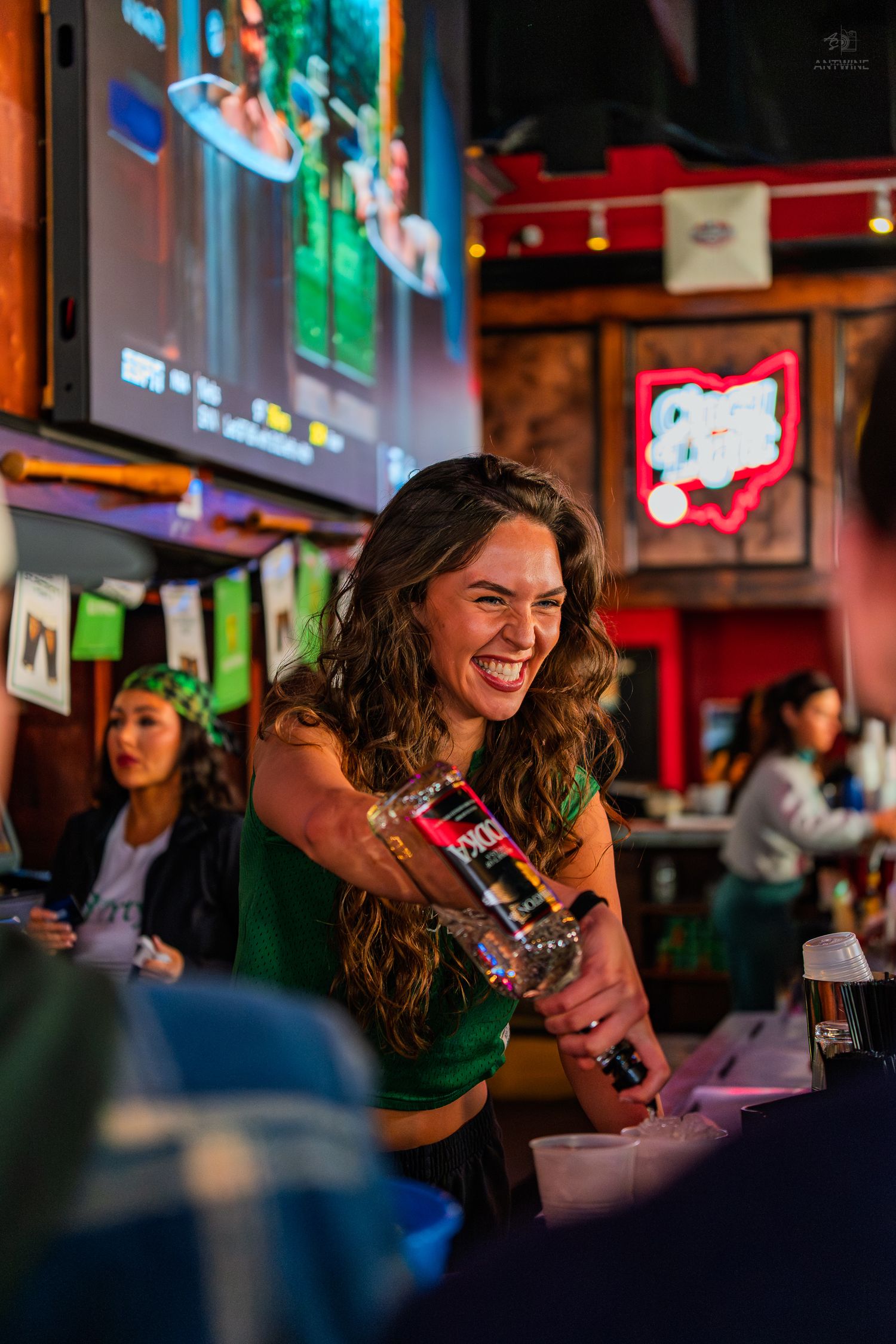 Smiling bartender pouring drinks at a lively St. Patrick's Day bar event.