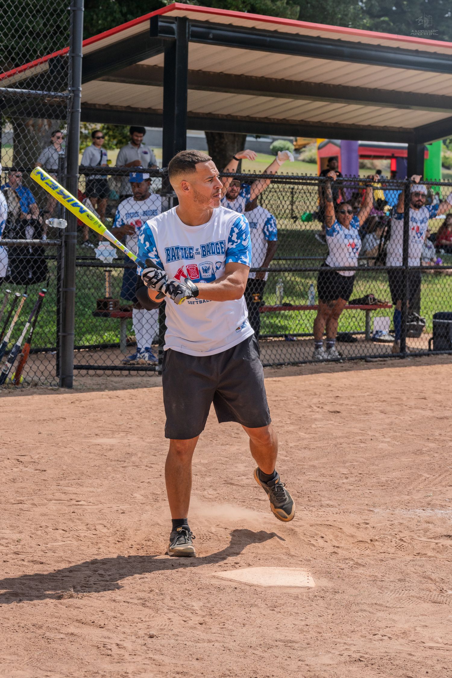 Male softball player swinging bat at home plate during game.
