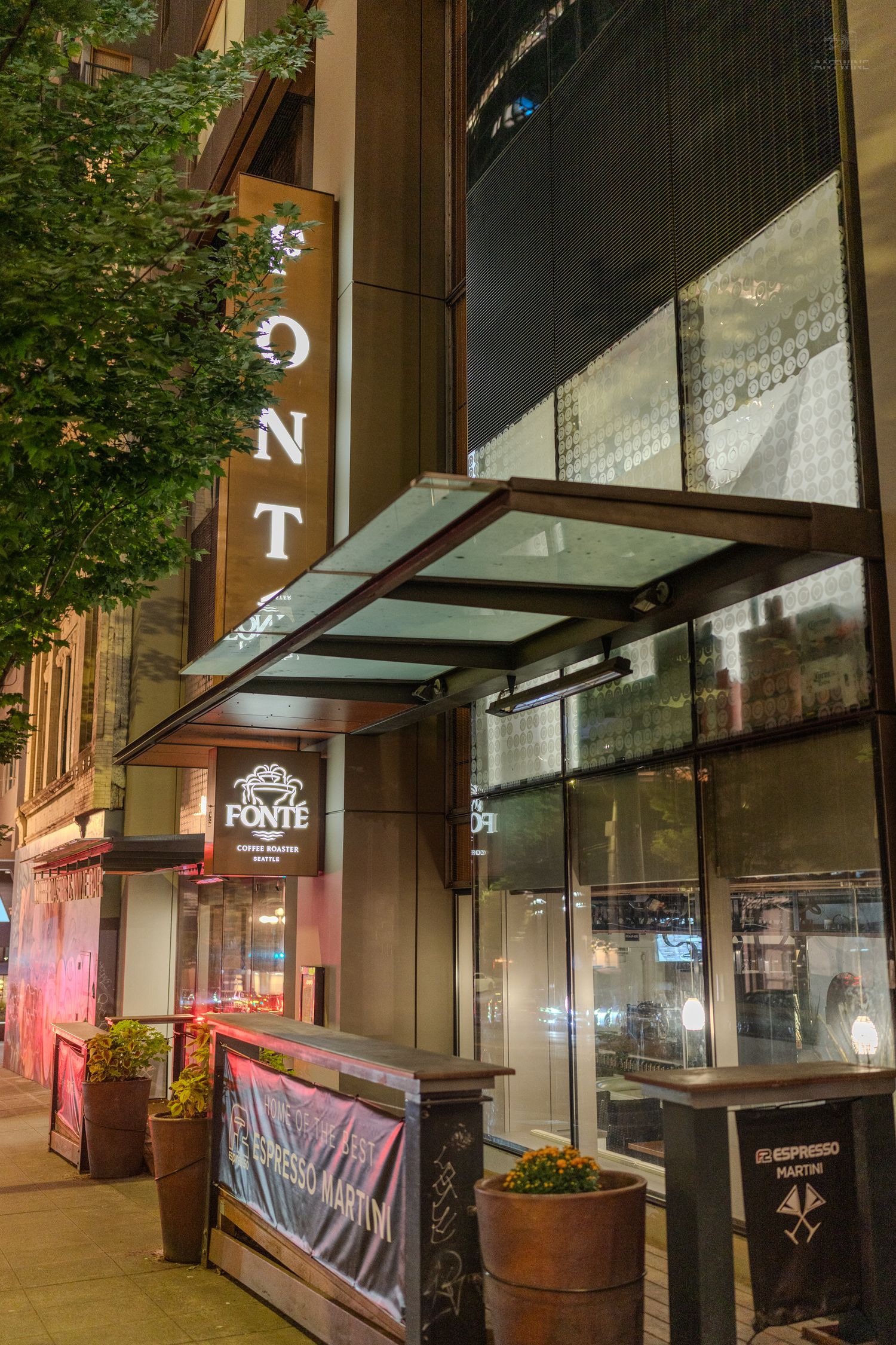 Fonte Coffee Roaster storefront at night with illuminated vertical sign and glass canopy entrance in Seattle.