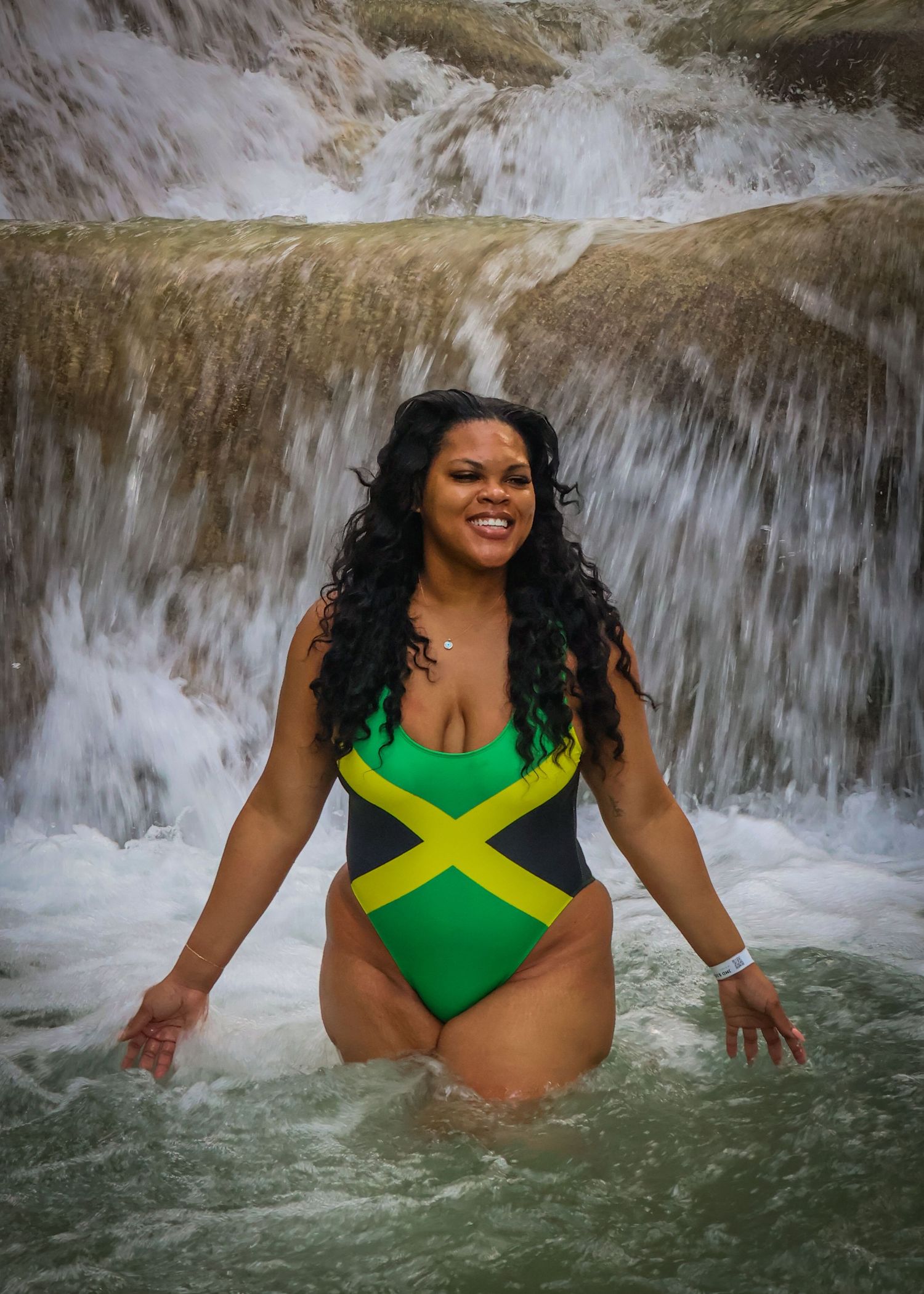 A female standing infront of a rushing waterfall.