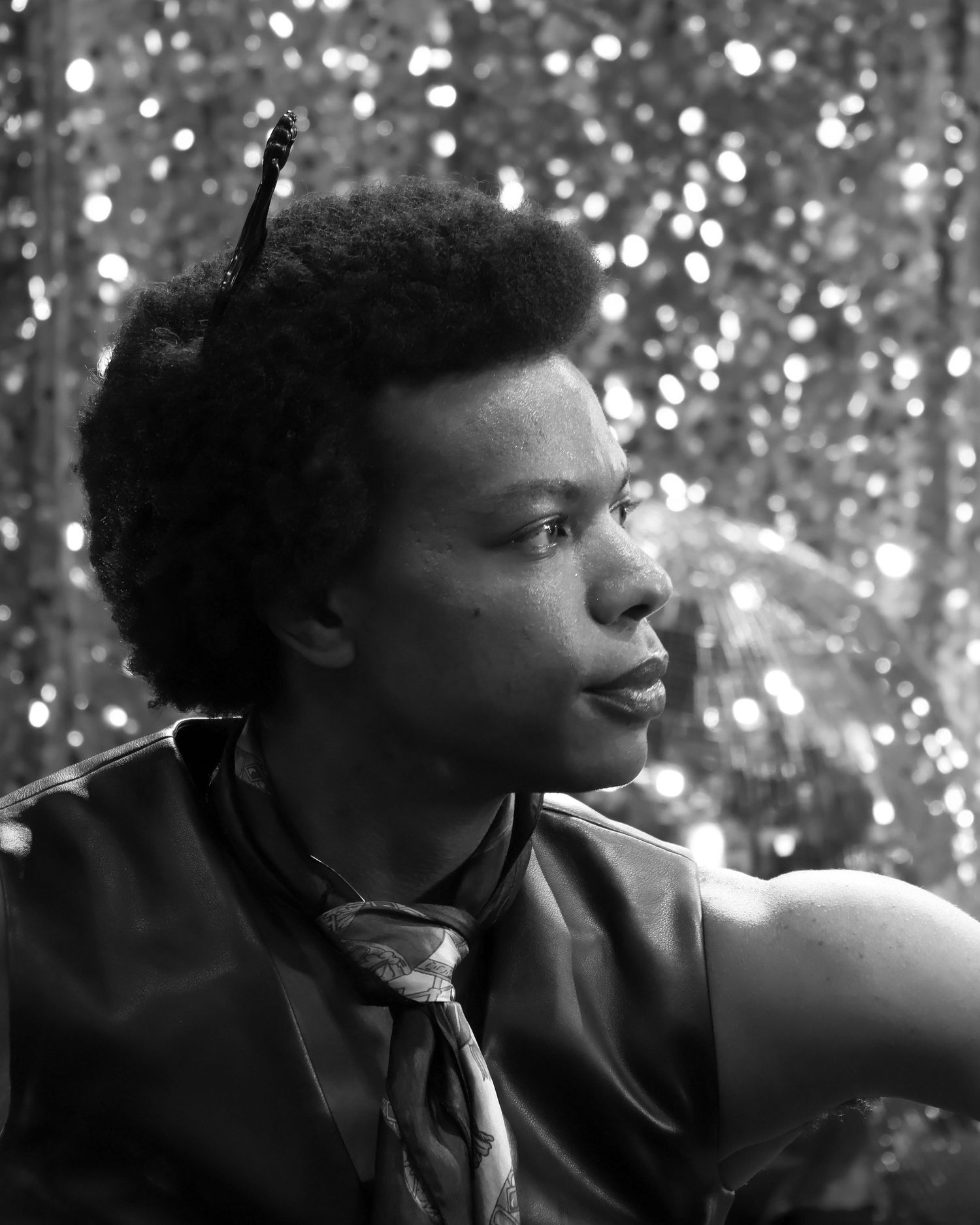 A black white headshot of a male infront of a shiny disco like background.