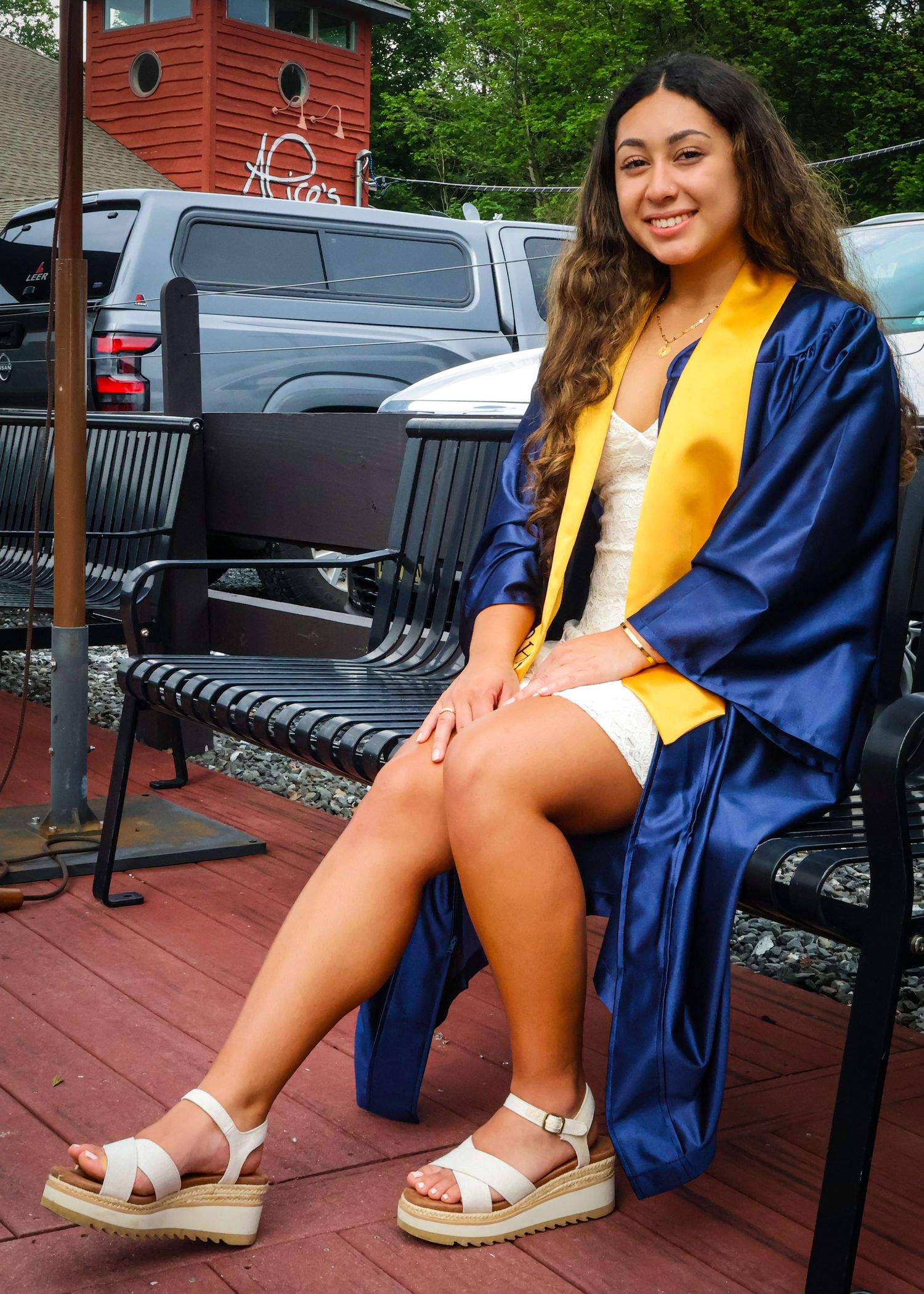 A female sitting on a bench in her graduation gown.