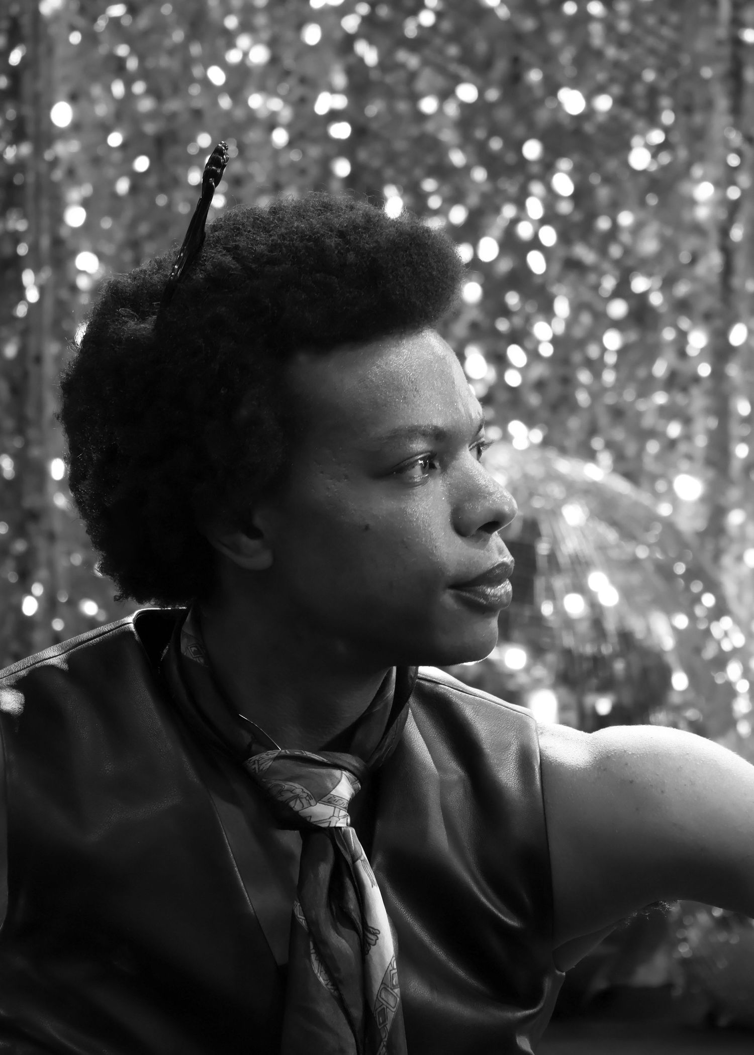 A black white headshot of a male infront of a shiny disco like background.