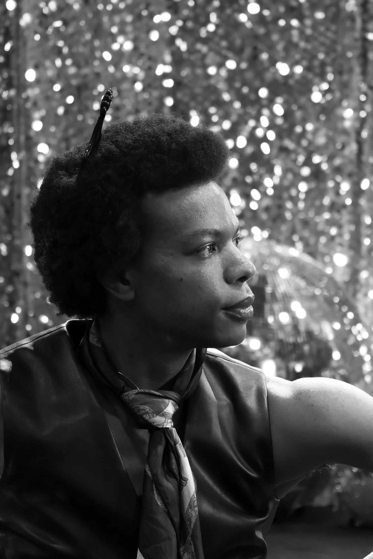 A black white headshot of a male infront of a shiny disco like background.