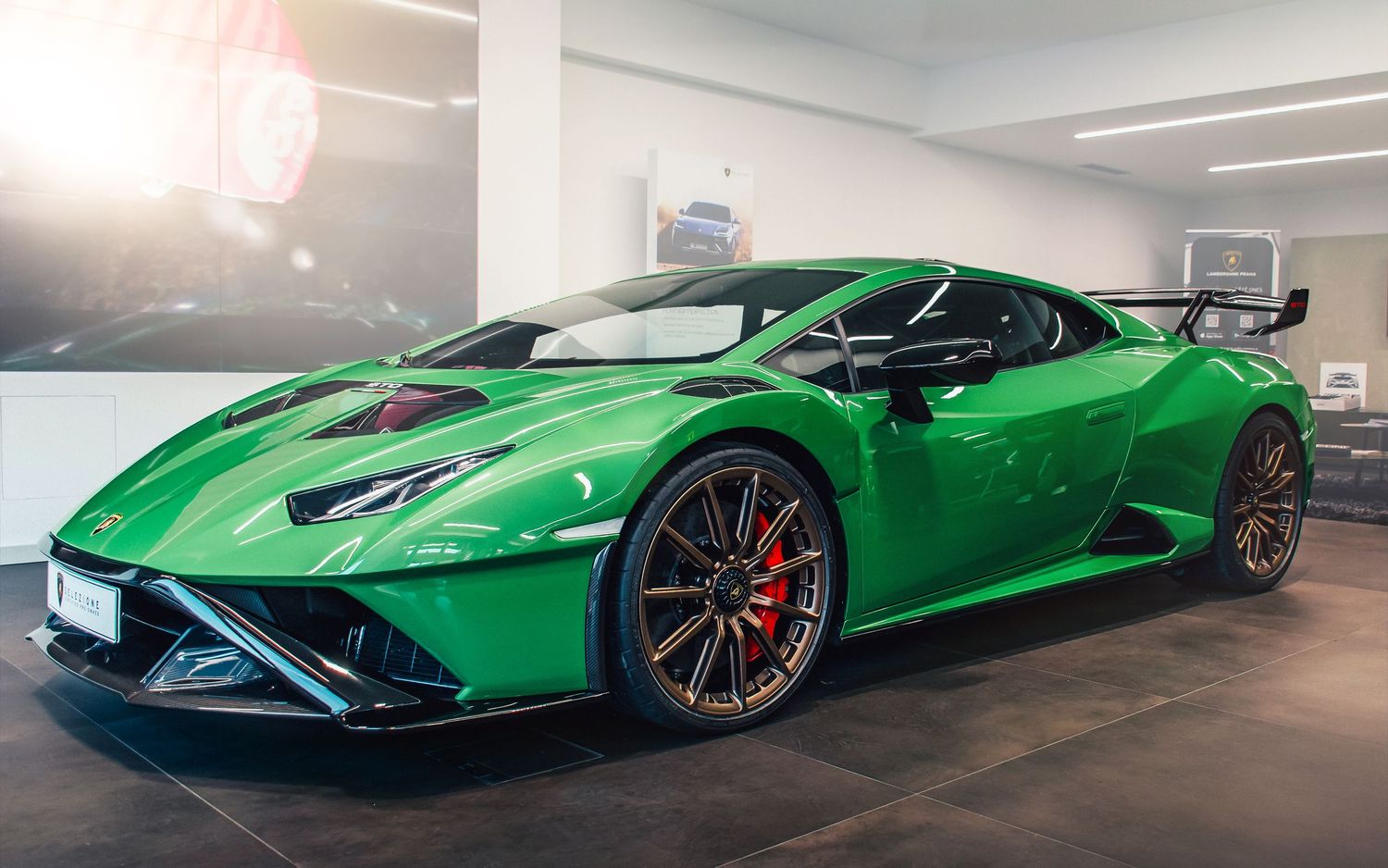 Green Lamborghini Huracan STO supercar displayed in a bright modern showroom.