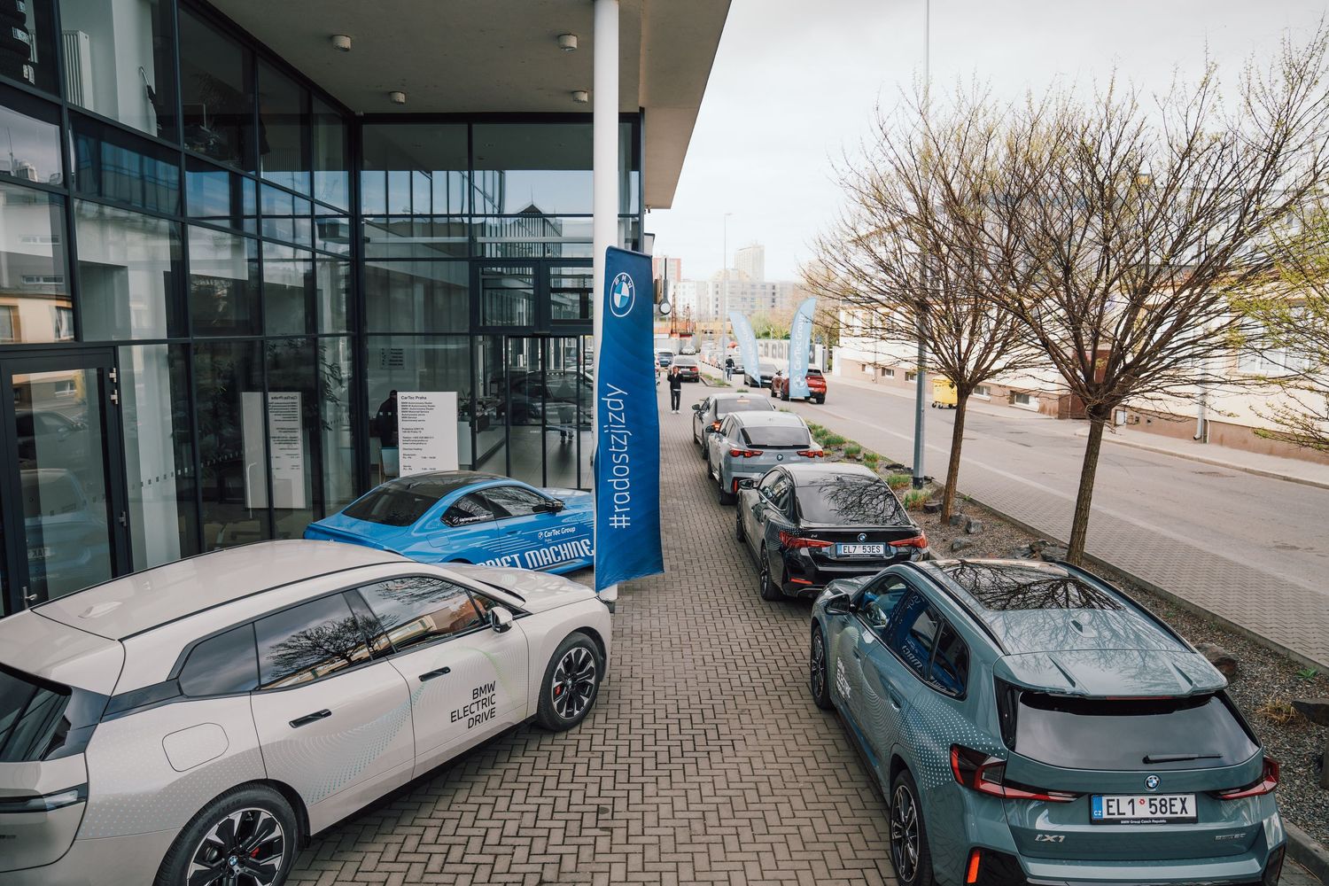 Row of BMW electric vehicles parked outside a modern glass dealership building.