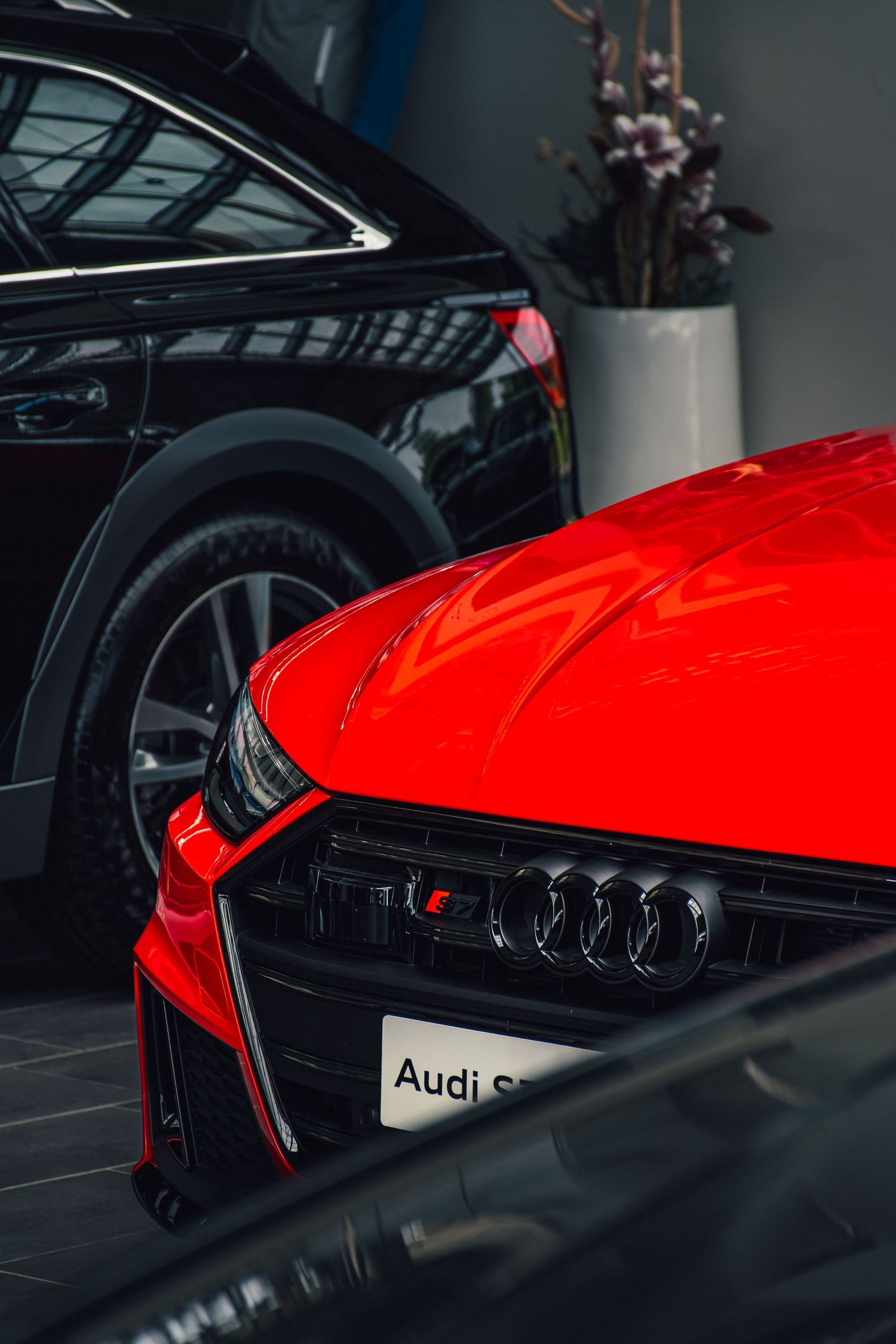 Close-up of a red Audi S model front grille with four rings logo displayed in a dealership showroom.