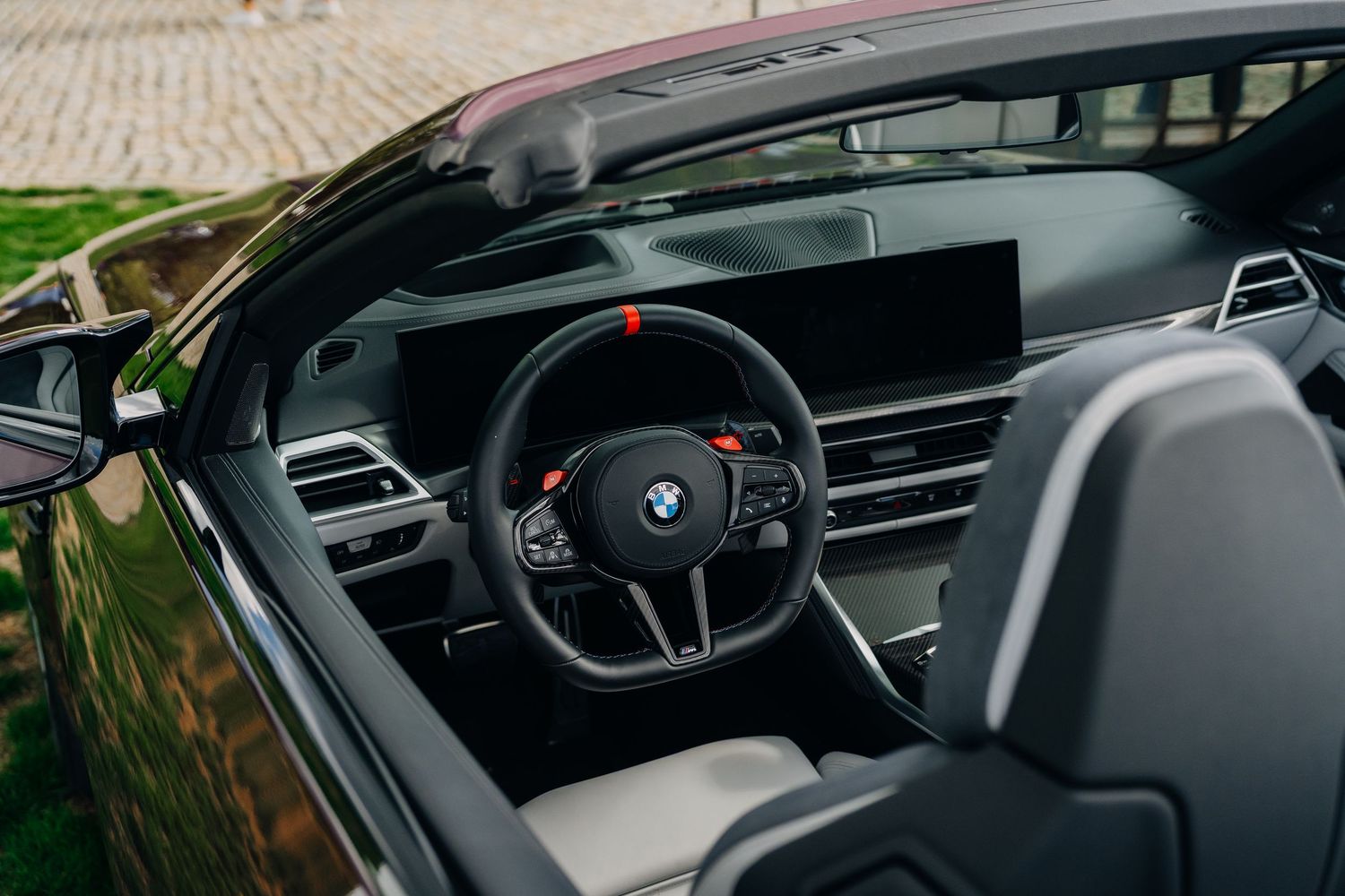 BMW M convertible interior featuring sport steering wheel, digital dashboard, and carbon fiber trim accents.