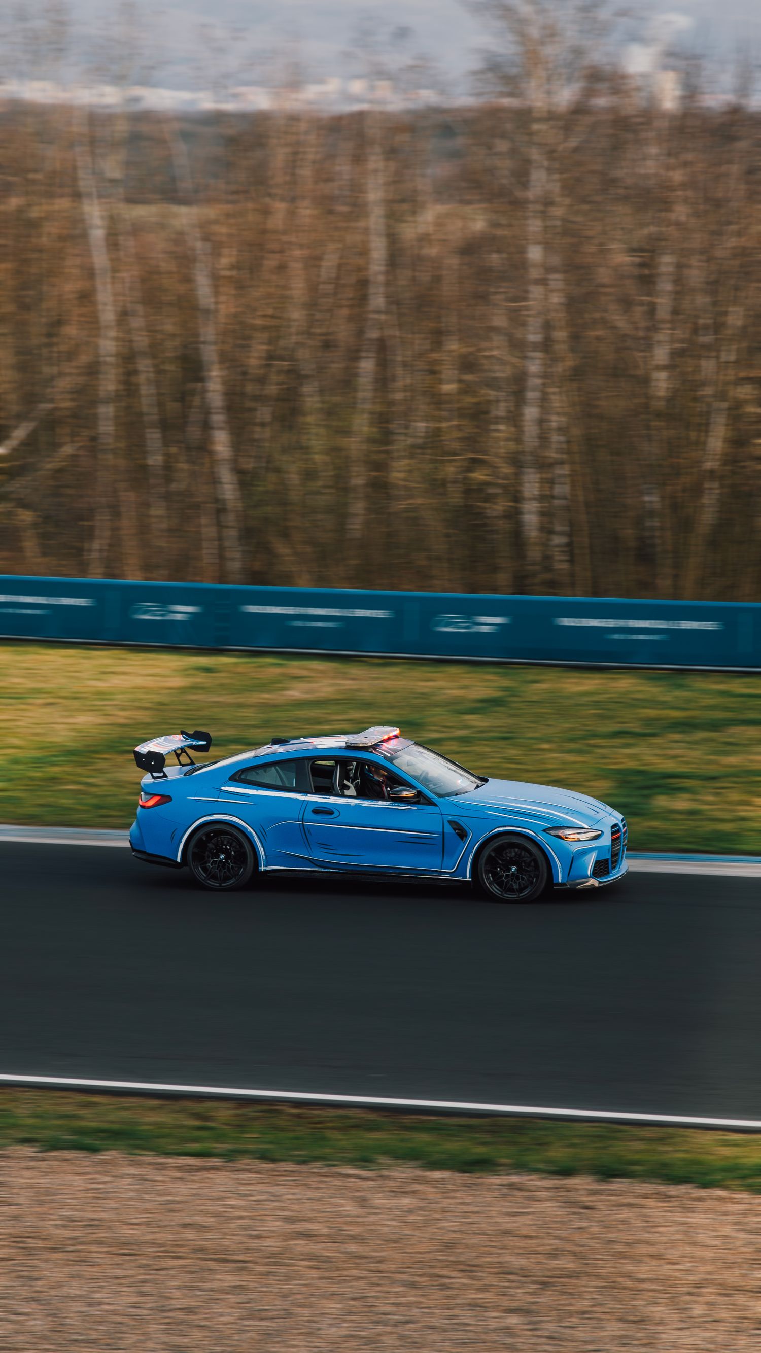 Blue BMW M4 GT3 racing at high speed on a circuit track with motion-blurred background.