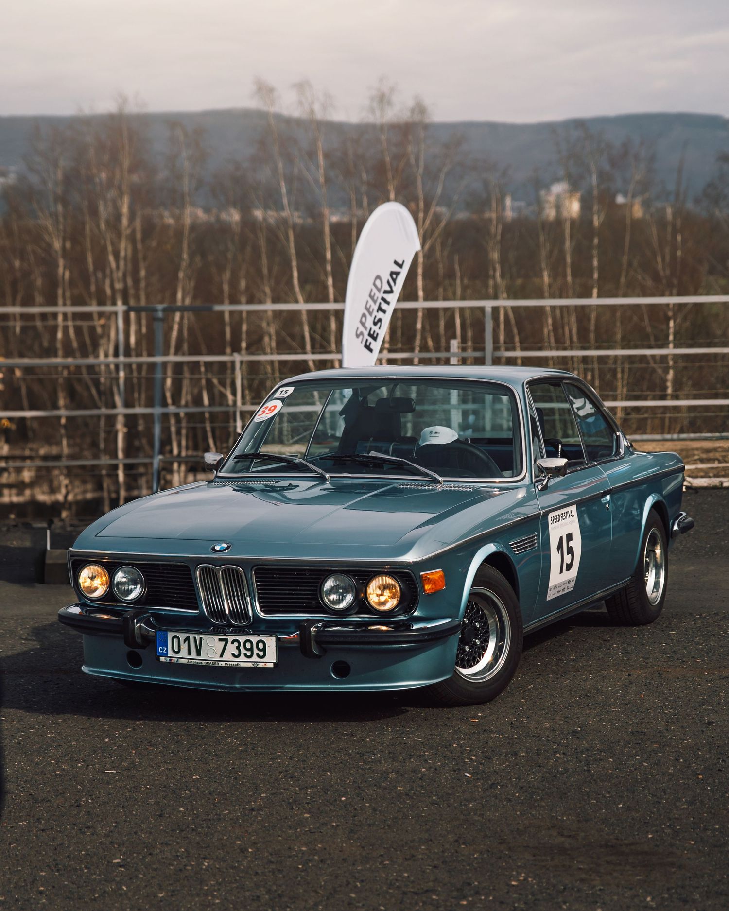 Vintage teal BMW 3.0 CS race car number 15 with Czech plates at a Speed Festival motorsport event.