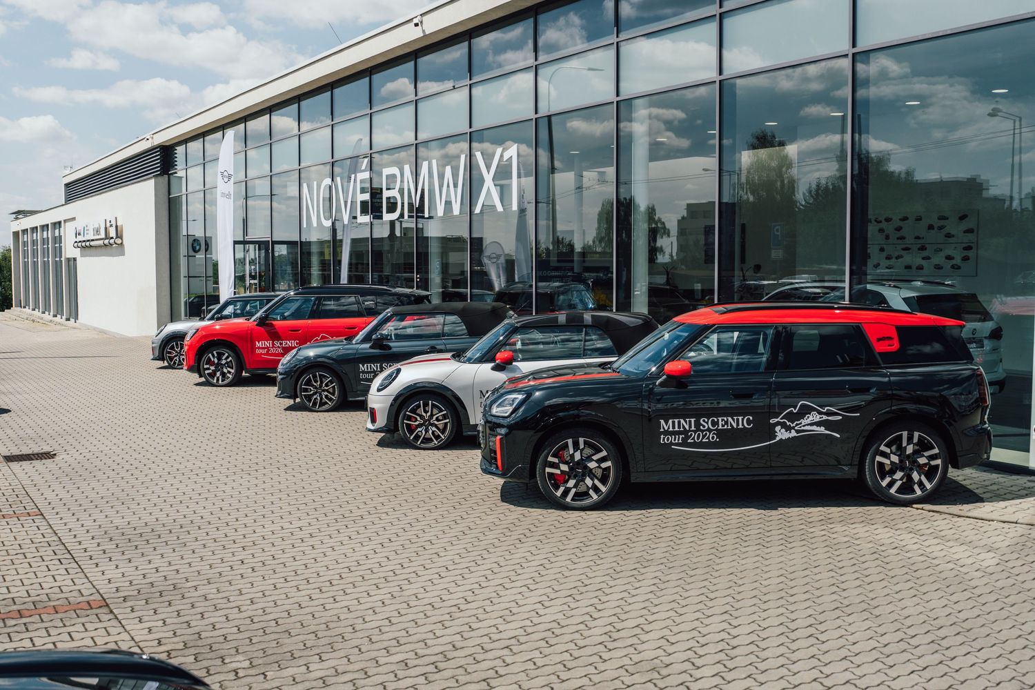 Multiple MINI Cooper models including a Countryman lined up outside a Nove BMW X1 dealership.