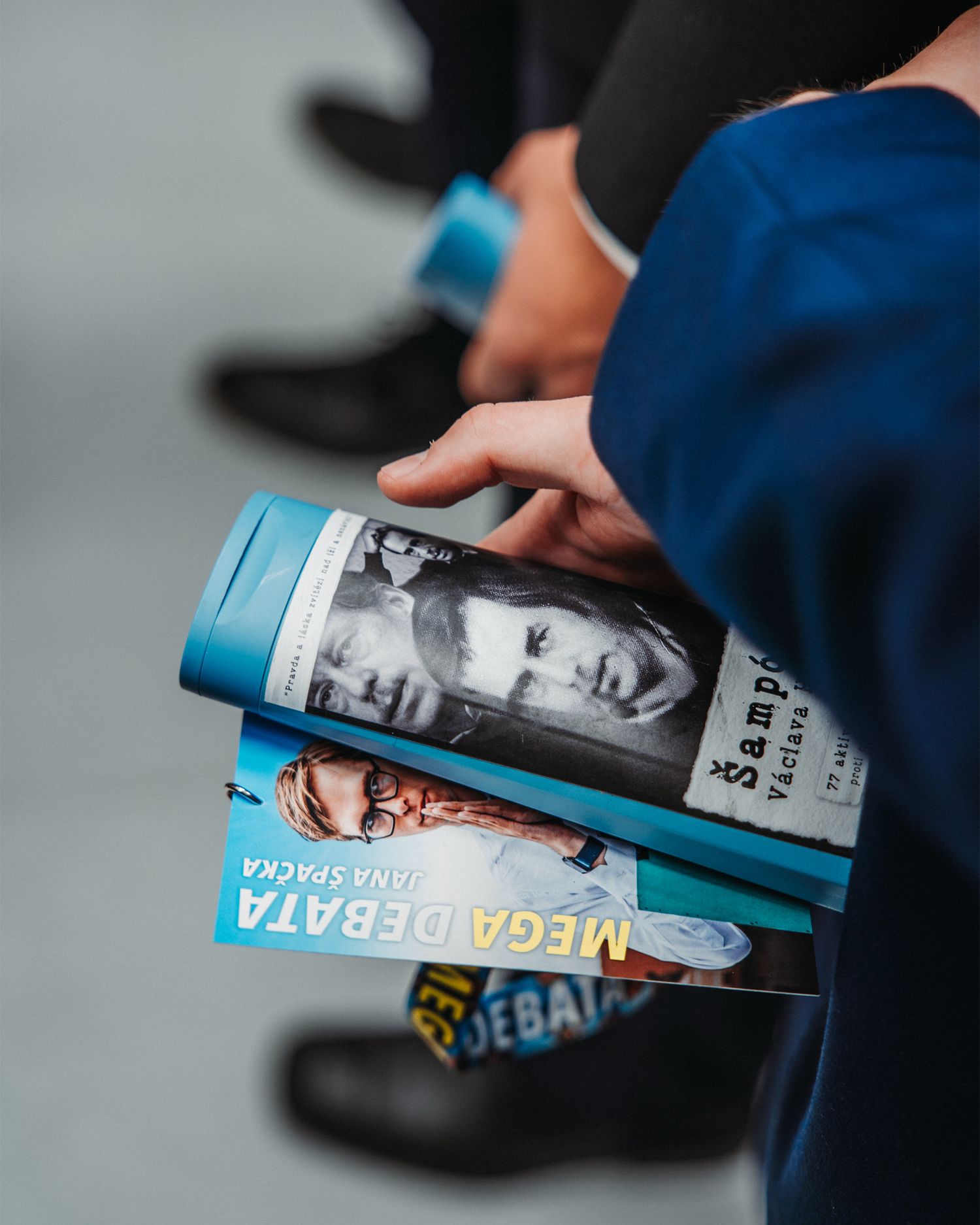 Close-up of hands holding Czech books including Mega Debata and Sampioni.
