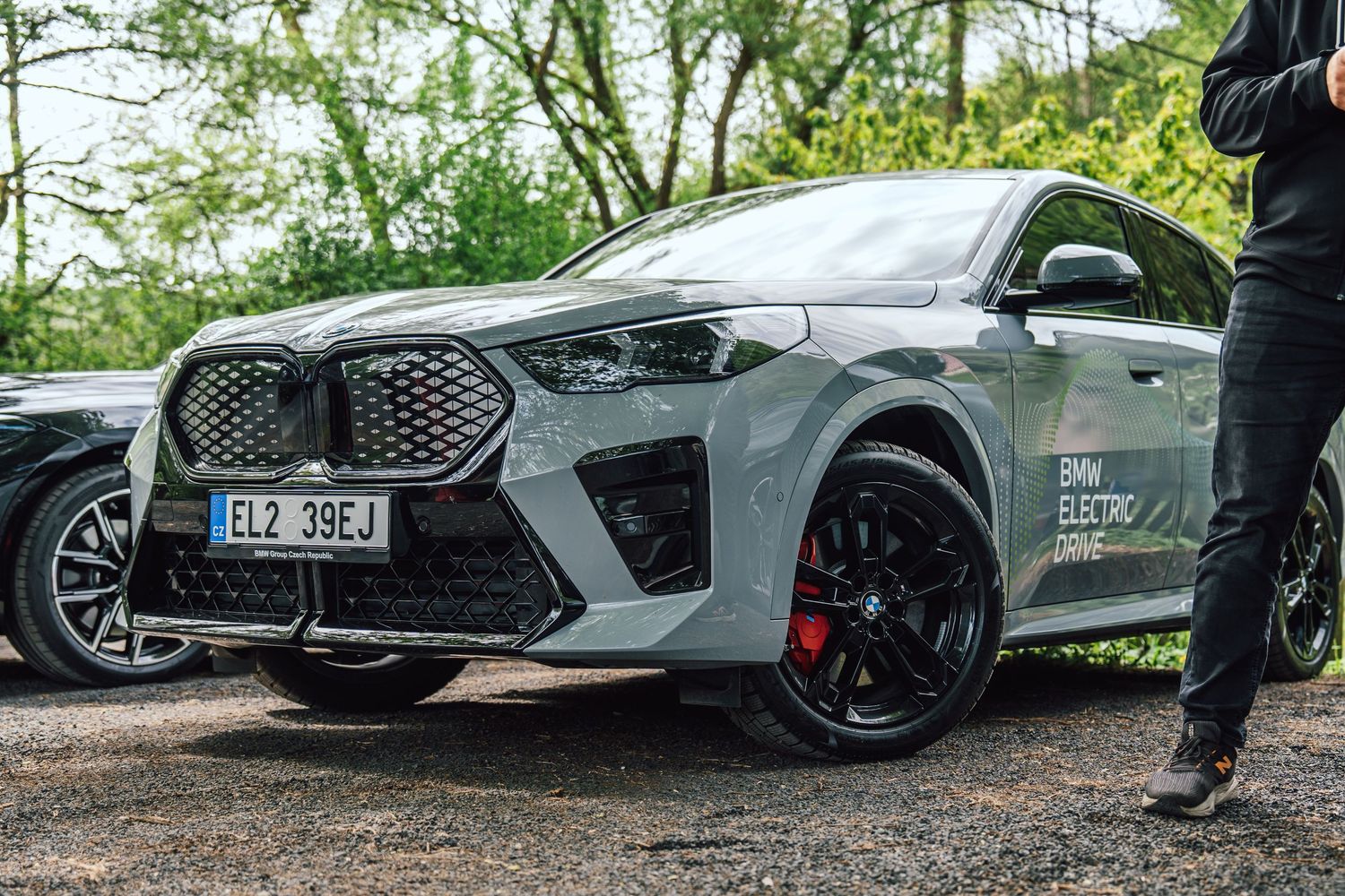 Front view of a grey BMW iX5 electric SUV with red brake calipers and BMW Electric Drive branding.