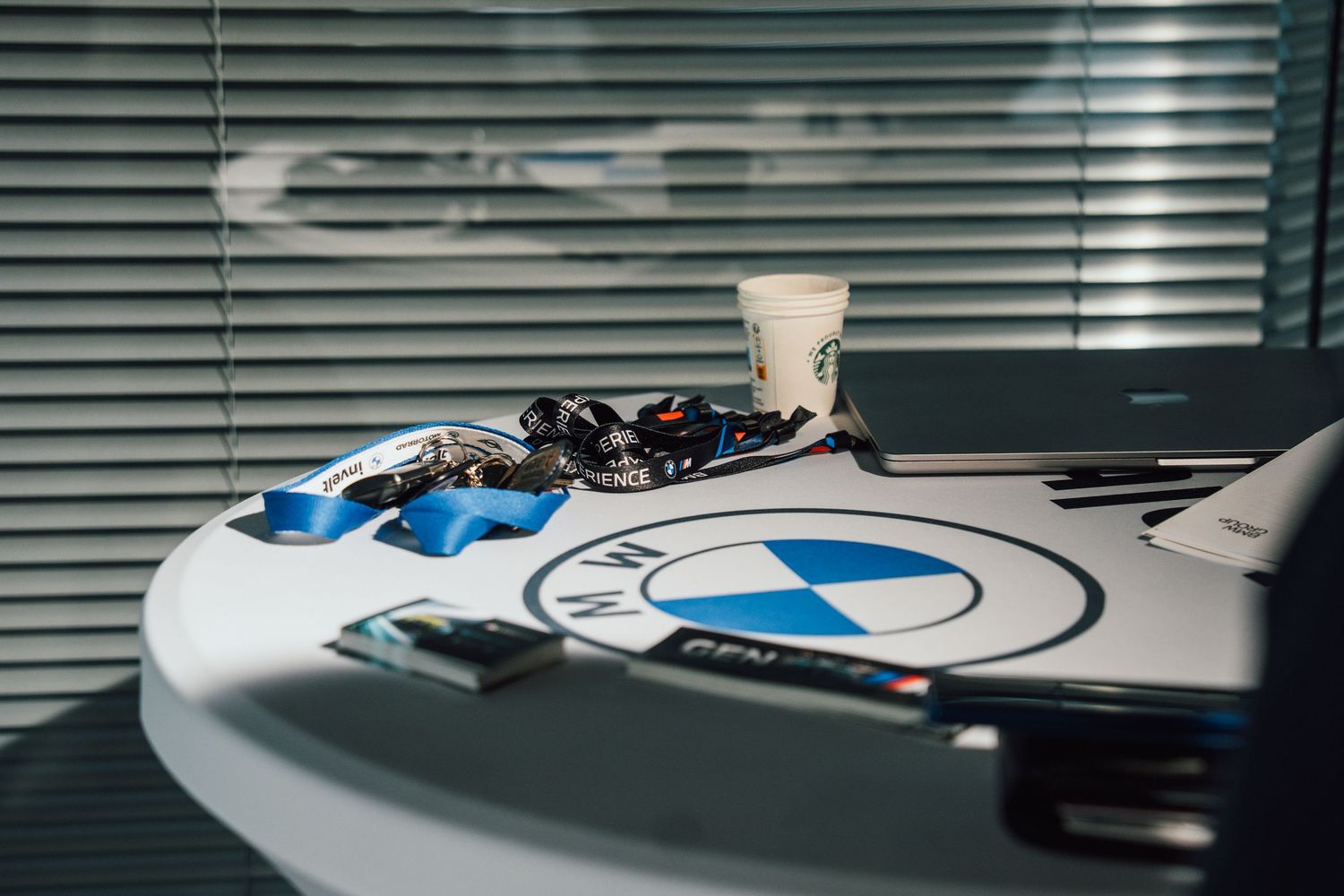 BMW branded table display with accessories, coffee cup, and promotional materials at a dealership event.