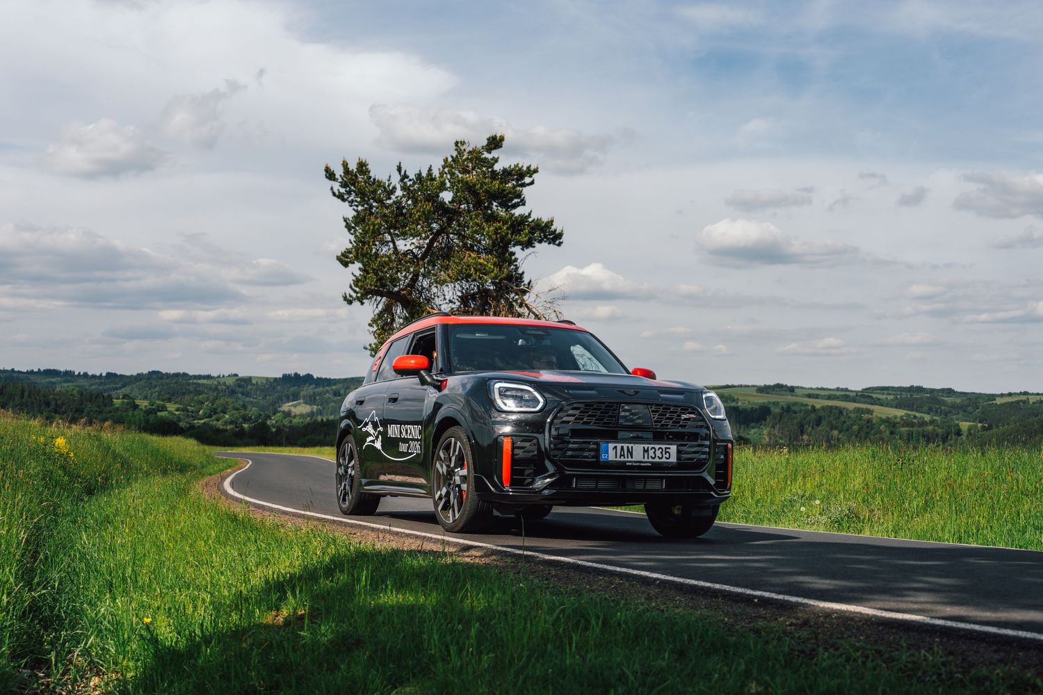 MINI Cooper JCW Countryman SUV driving on a rural road surrounded by lush green countryside.