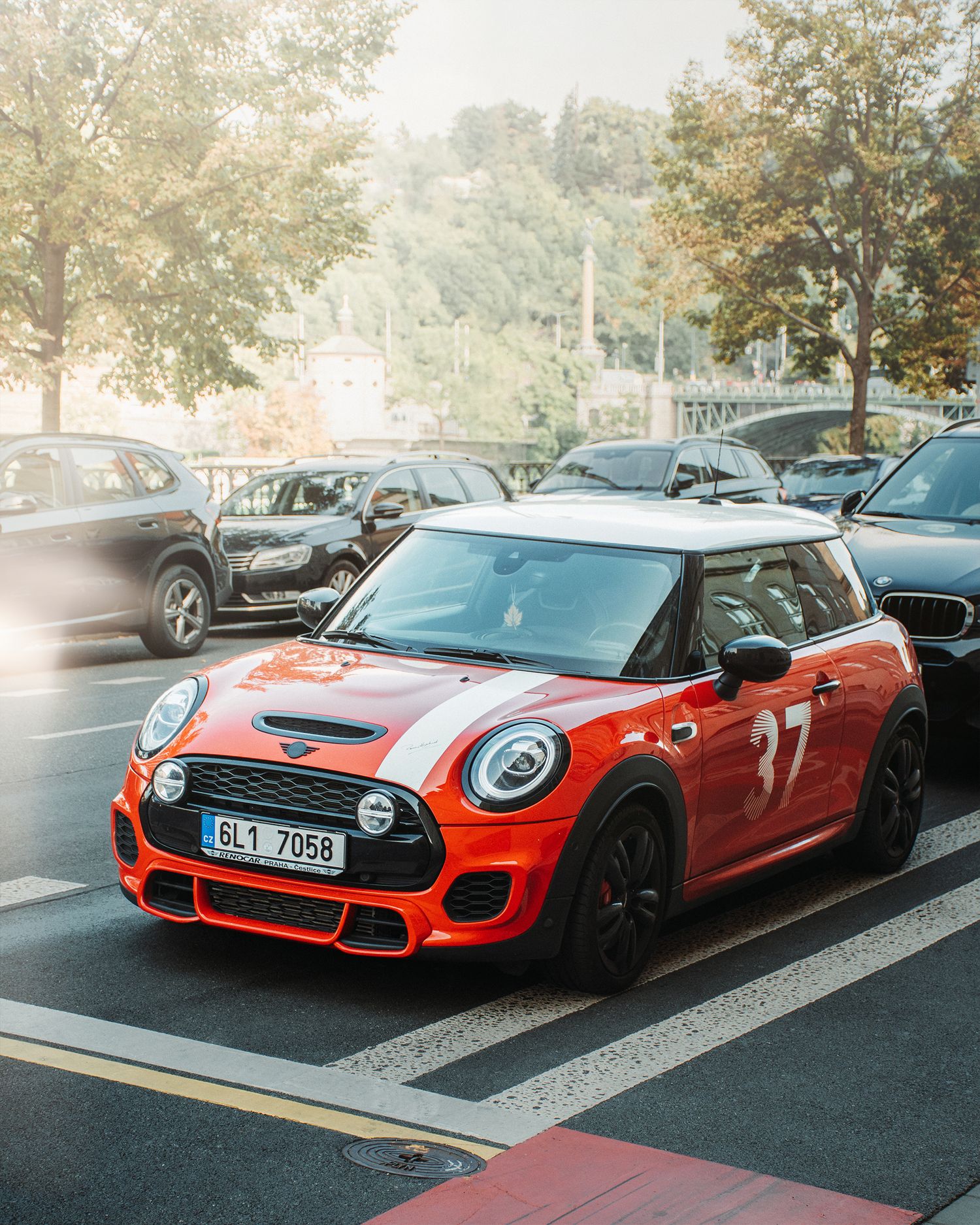 Red Mini Cooper JCW number 37 with Czech license plate parked in a sunny urban parking area.