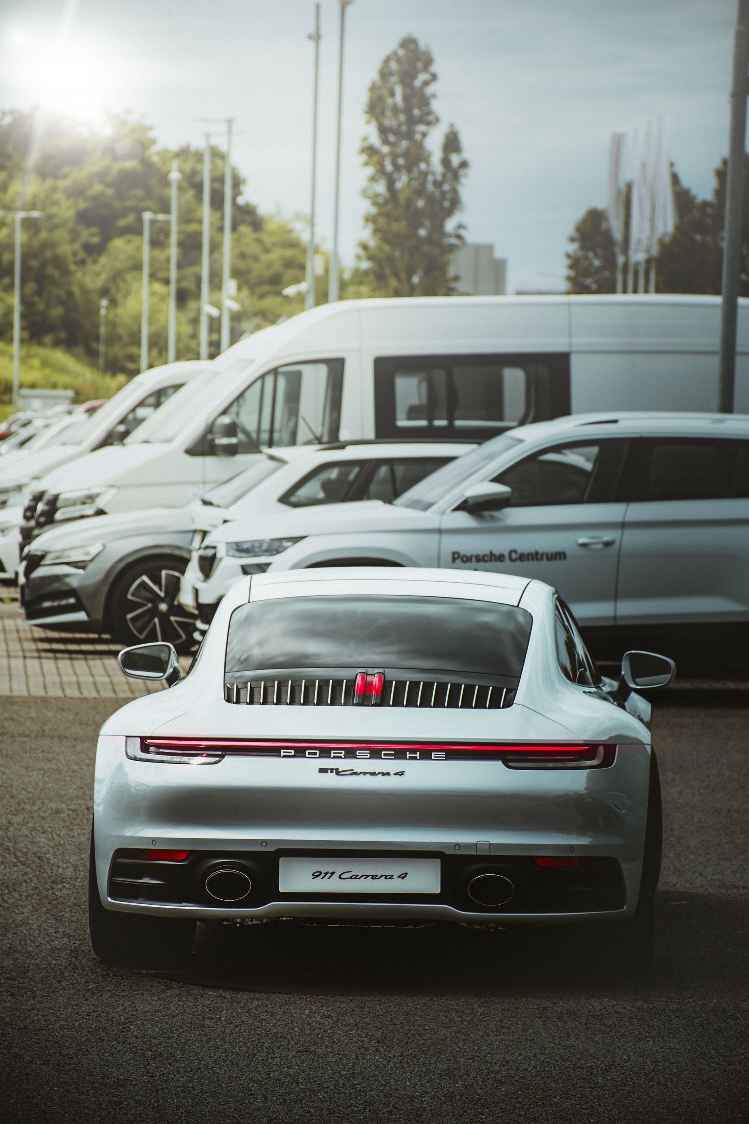 Rear view of a silver Porsche 911 Carrera 4 parked at a Porsche Centrum dealership.