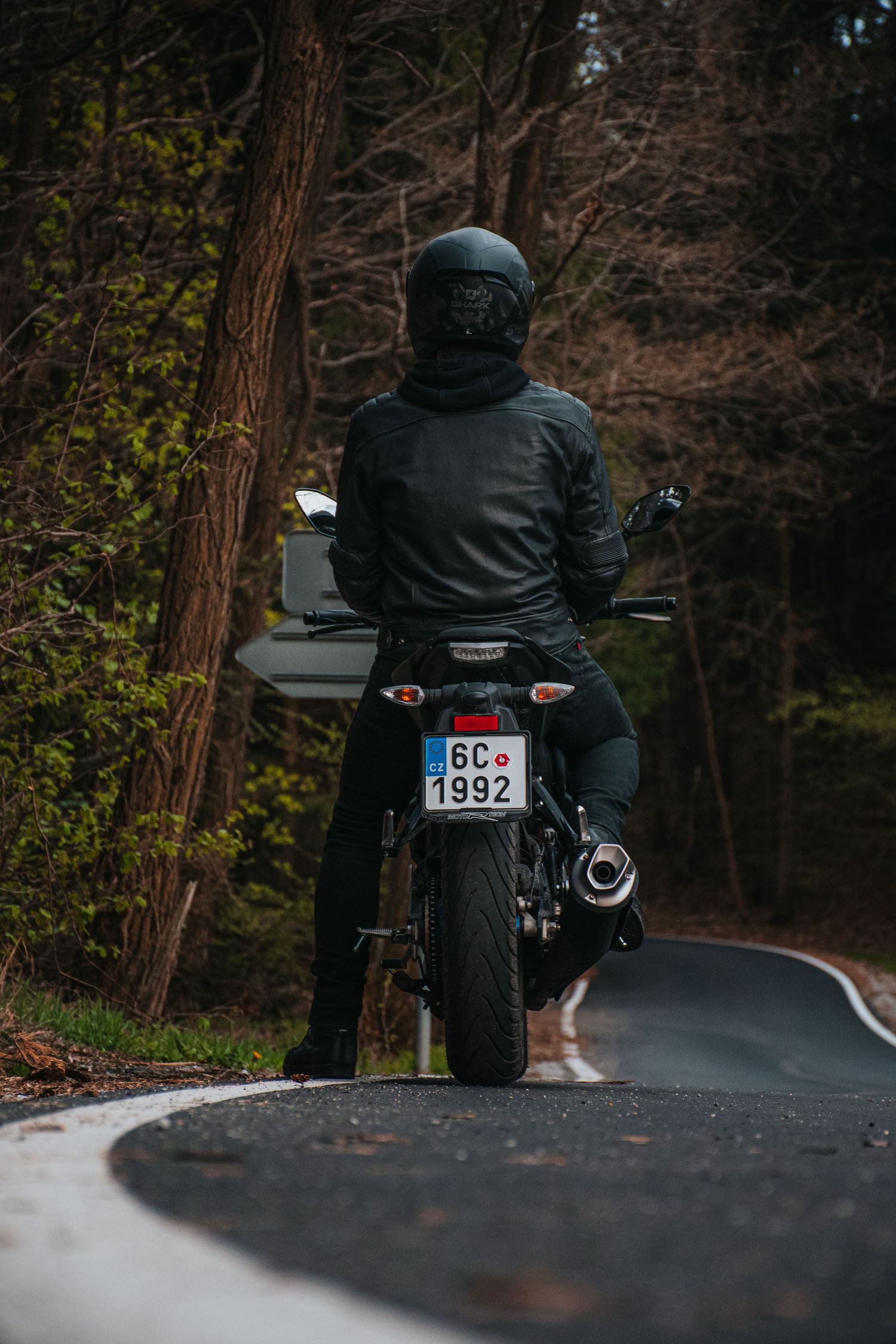 Rear view of biker in black gear on Yamaha MT on wet road.