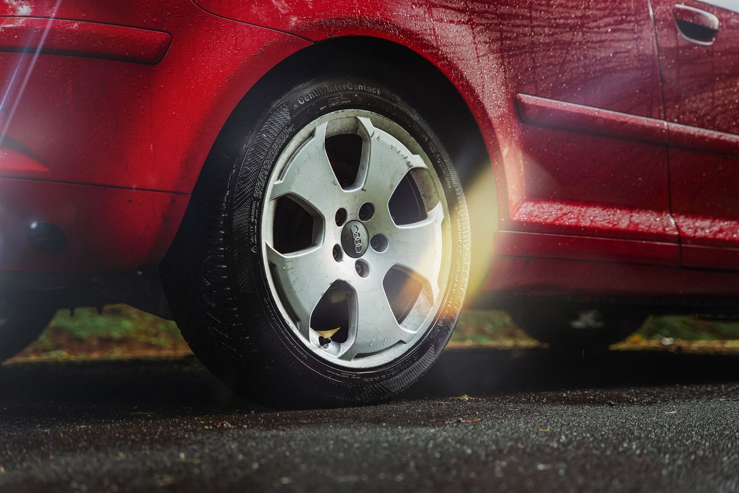 Close-up of a spinning red car wheel with alloy rim showing motion blur on asphalt.