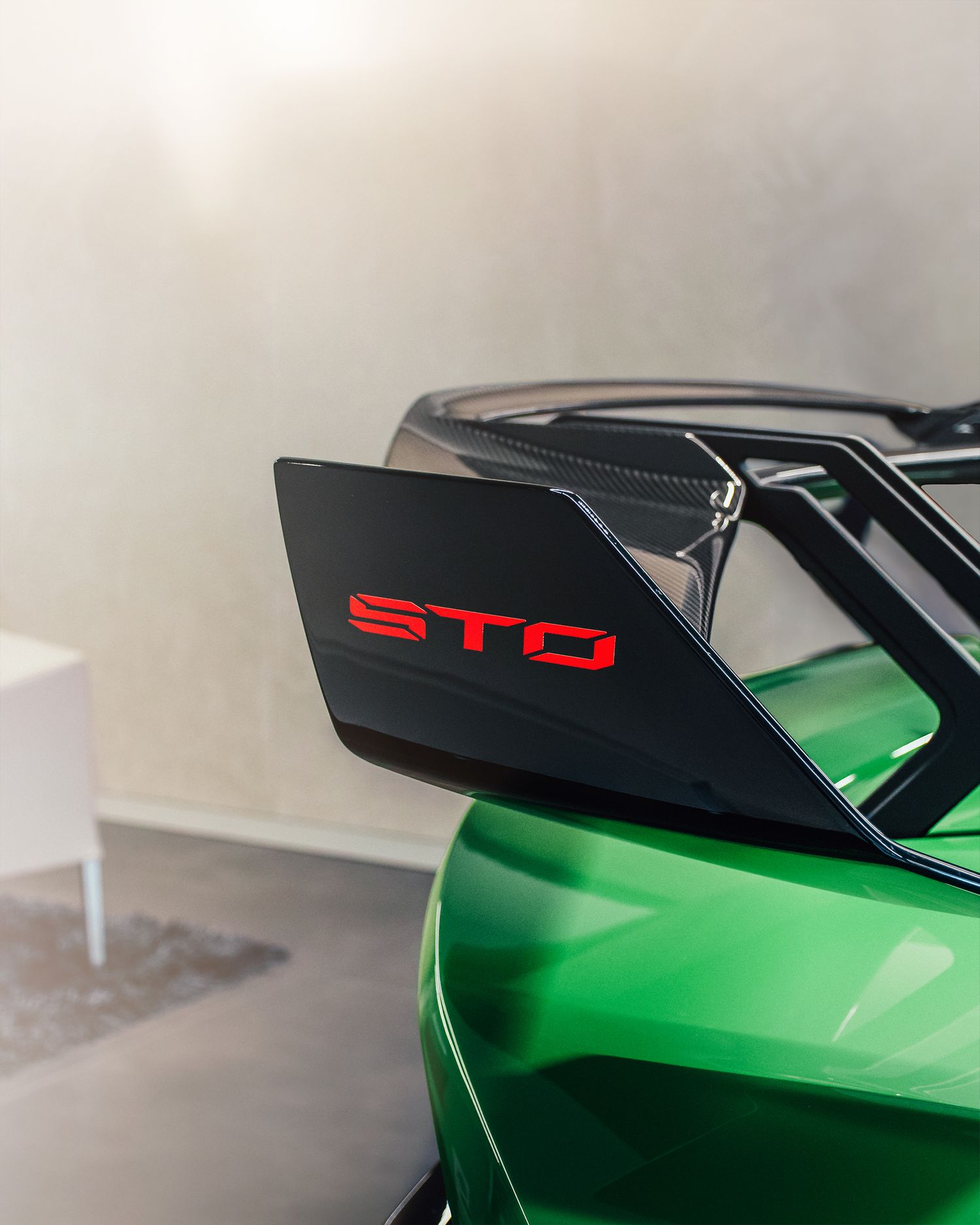 Close-up of a green Lamborghini Huracan STO carbon fiber rear wing with red STO lettering.