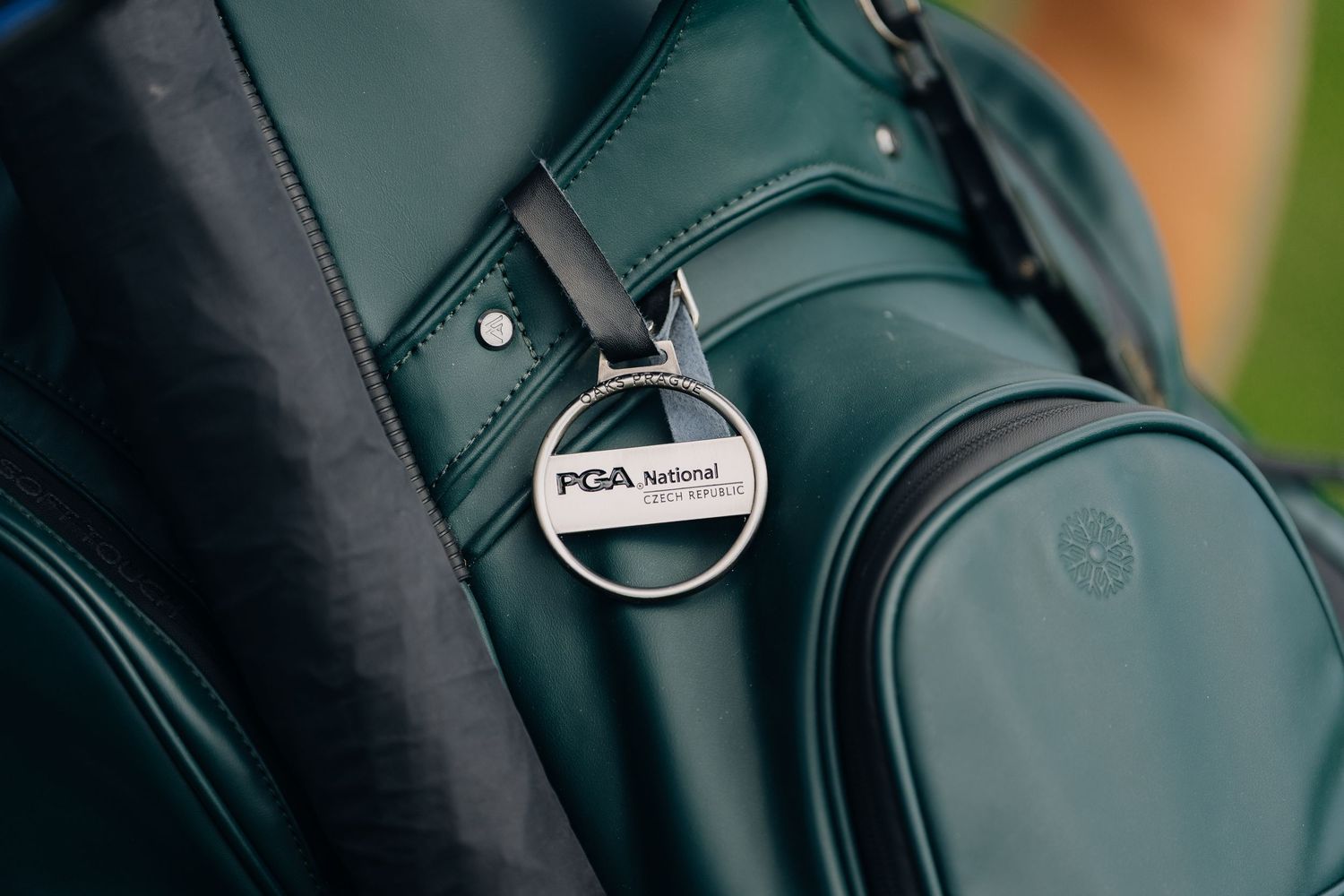 Close-up of a PGA National golf bag tag on a dark green leather golf bag.