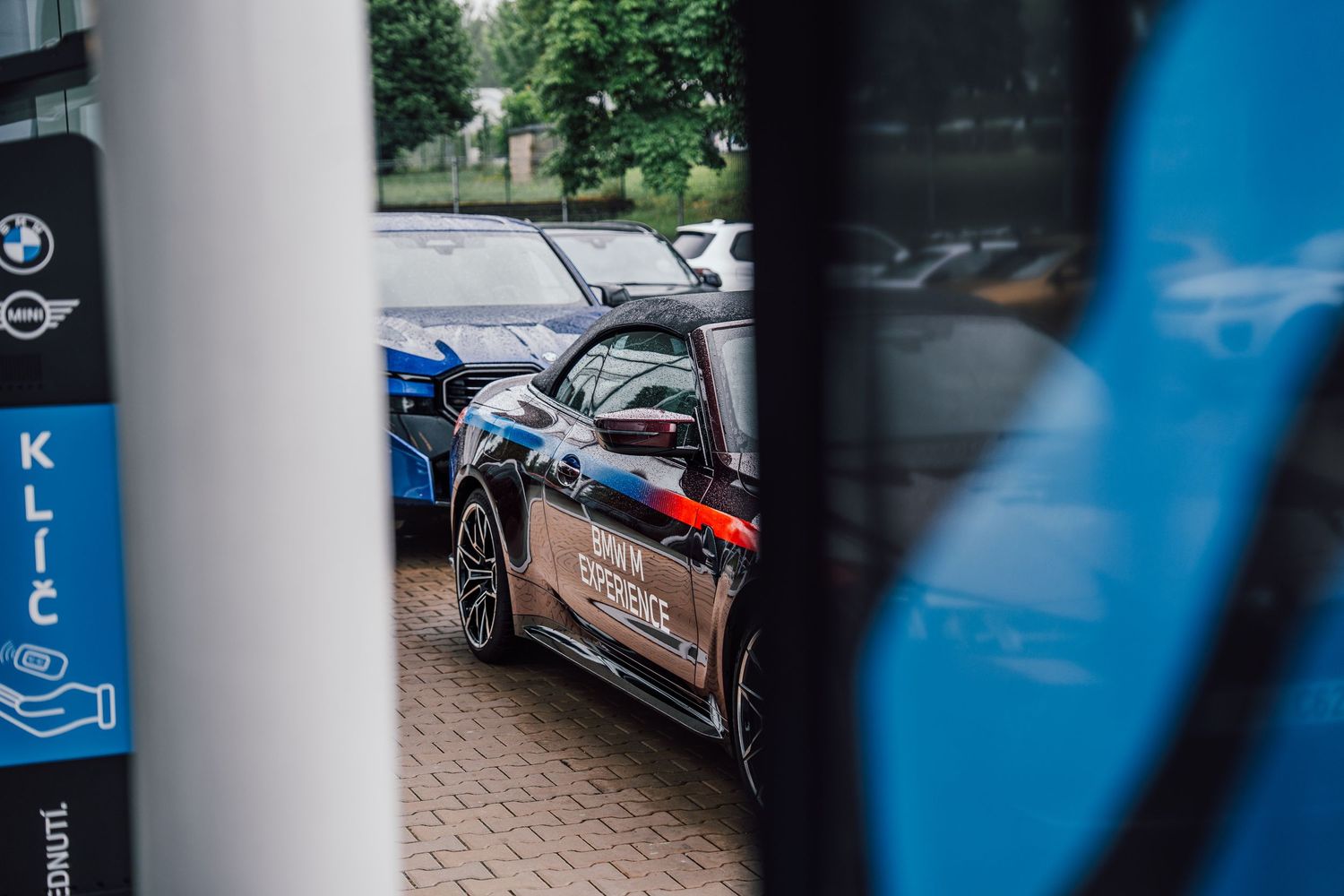 Close-up view of BMW Experience branded vehicles parked at a BMW and MINI dealership.