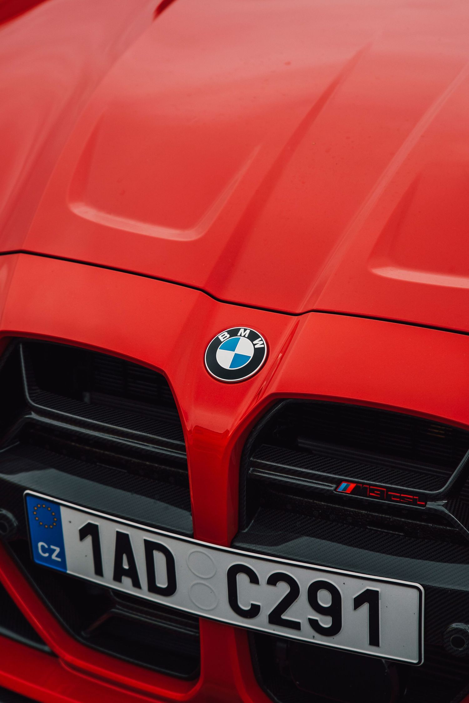 Red BMW M3 G80 front grille close-up with BMW badge and Czech license plate 1AD C291.