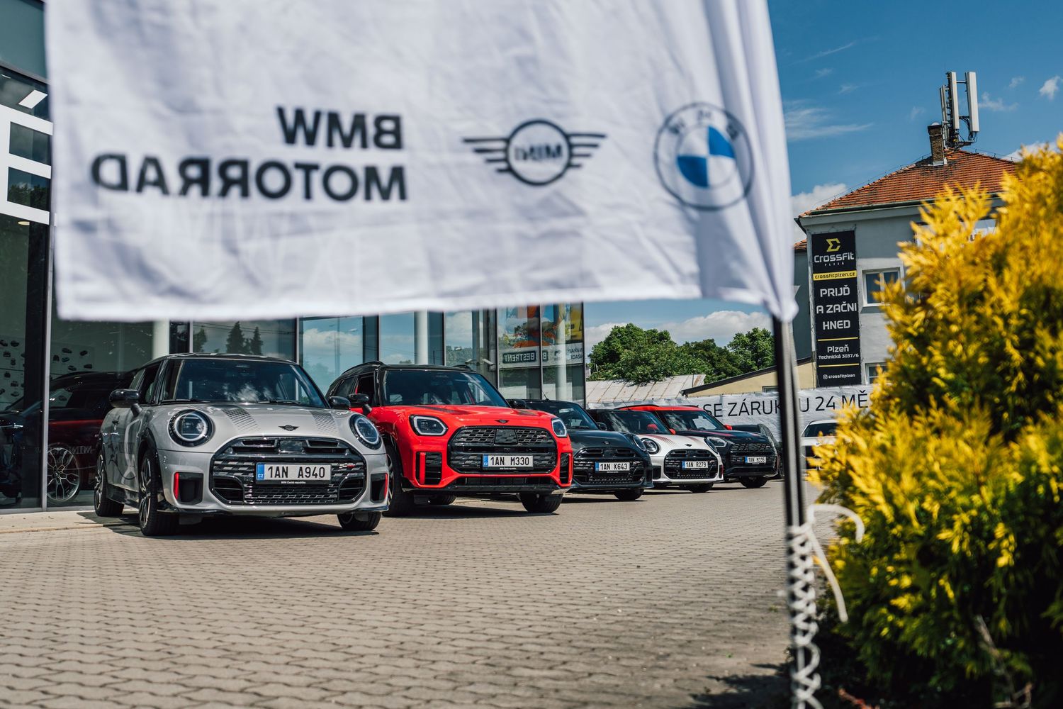 BMW Motorrad dealership exterior with a row of colorful MINI Cooper cars parked in the lot.