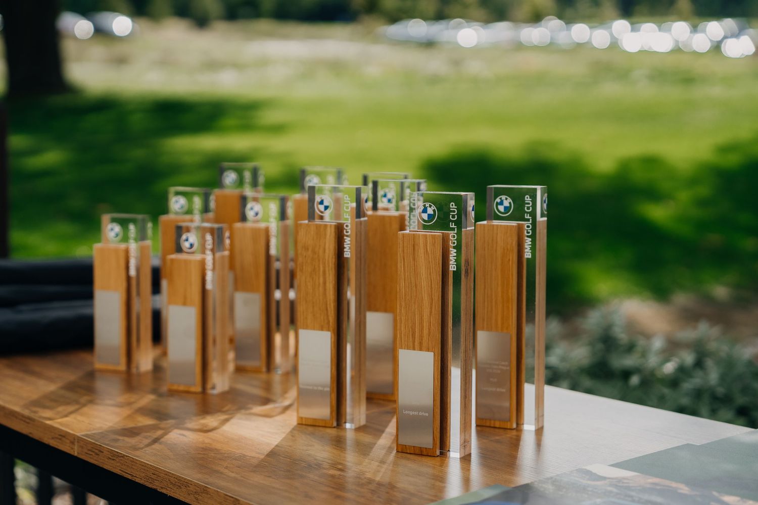 Row of elegant wooden and acrylic trophy awards displayed on a table at a golf tournament.