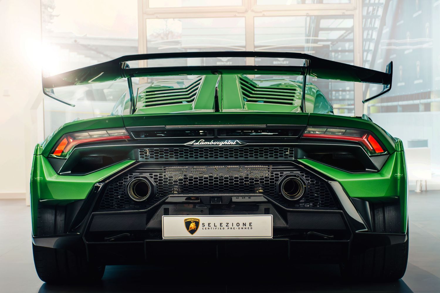 Rear view of a green Lamborghini Huracan STO with large spoiler and dual exhausts.