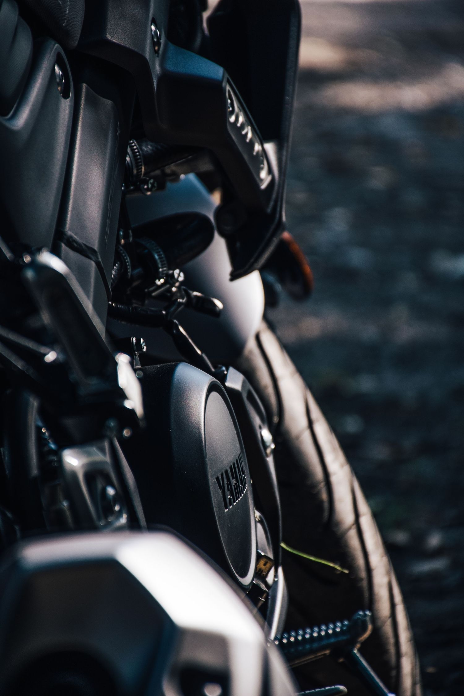 Close-up detail shot of a black Yamaha motorcycle engine and frame components in moody lighting.
