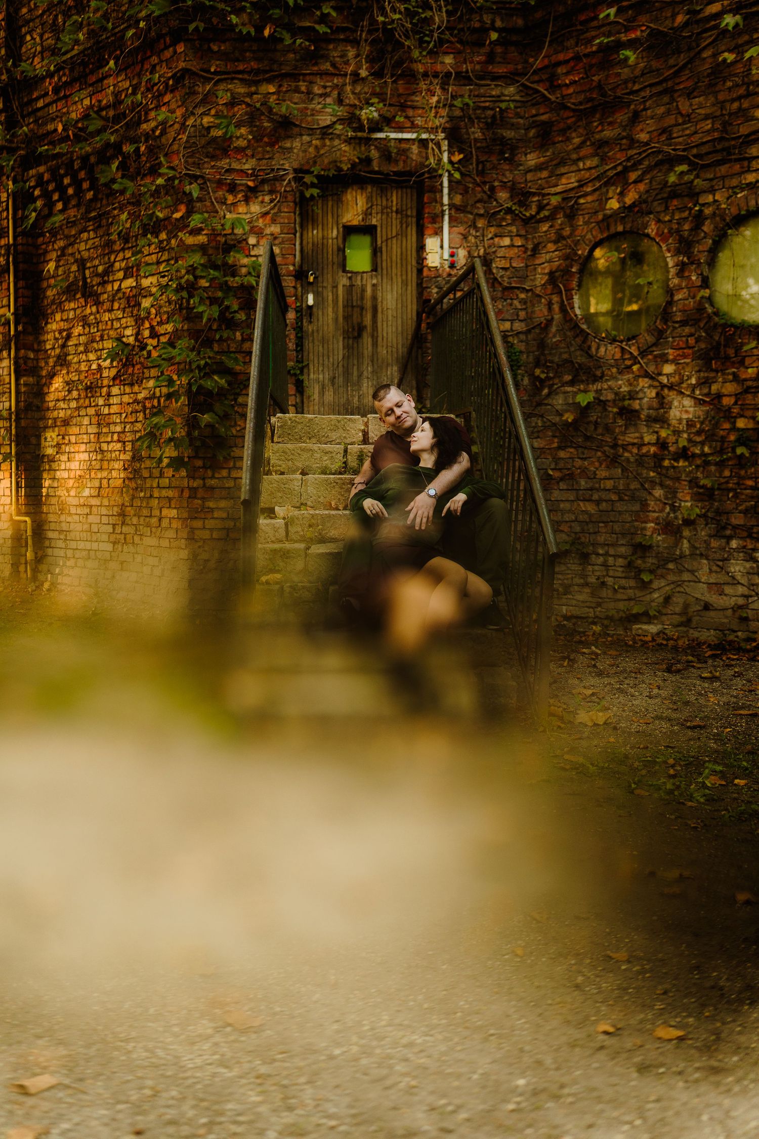 Couple sitting on brick staircase at night with atmospheric lighting.