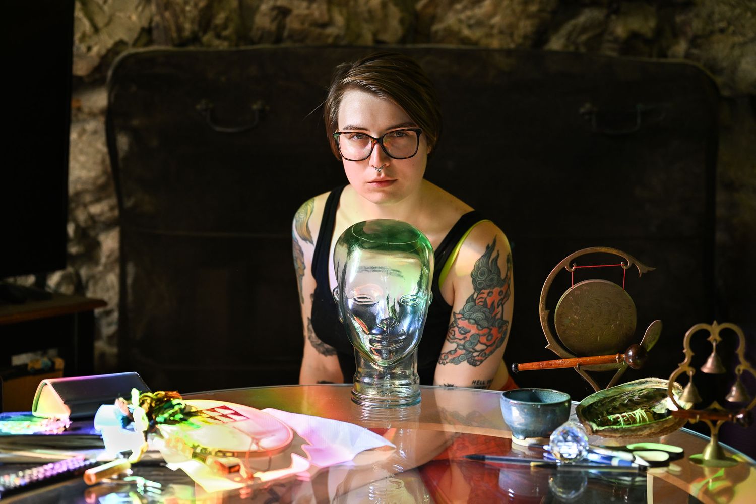 self portrait of the photographer in her living room with a variety of objects in front of her on a low table