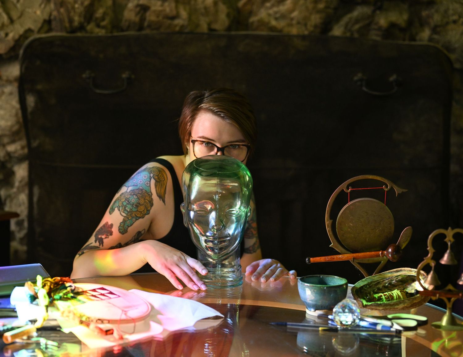 a self portrait of the photographer facing the camera and obscuring herself behind a clear glass head in front of her on