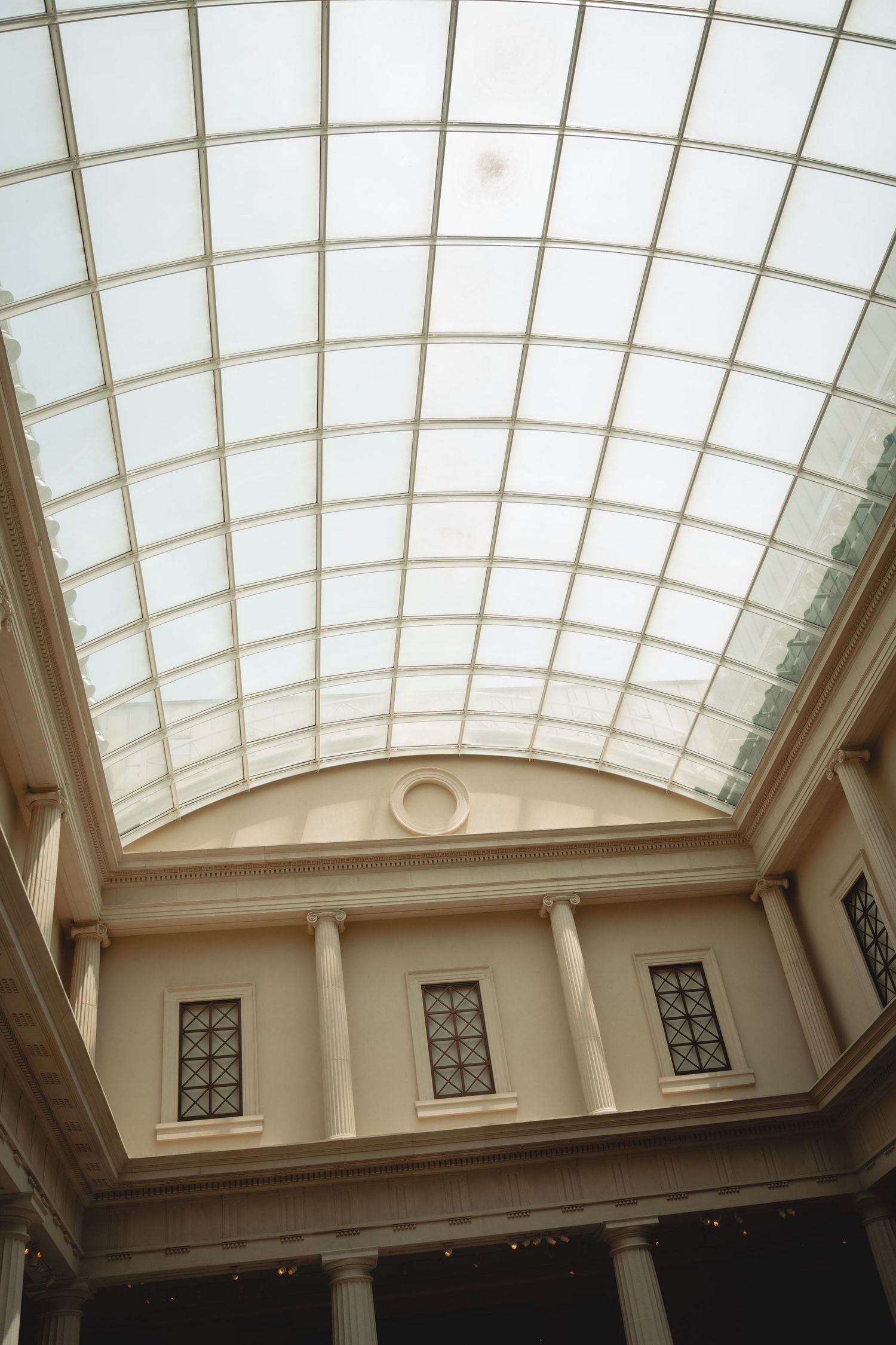 Interior view of a classic building featuring a large arched glass skylight ceiling and columns.