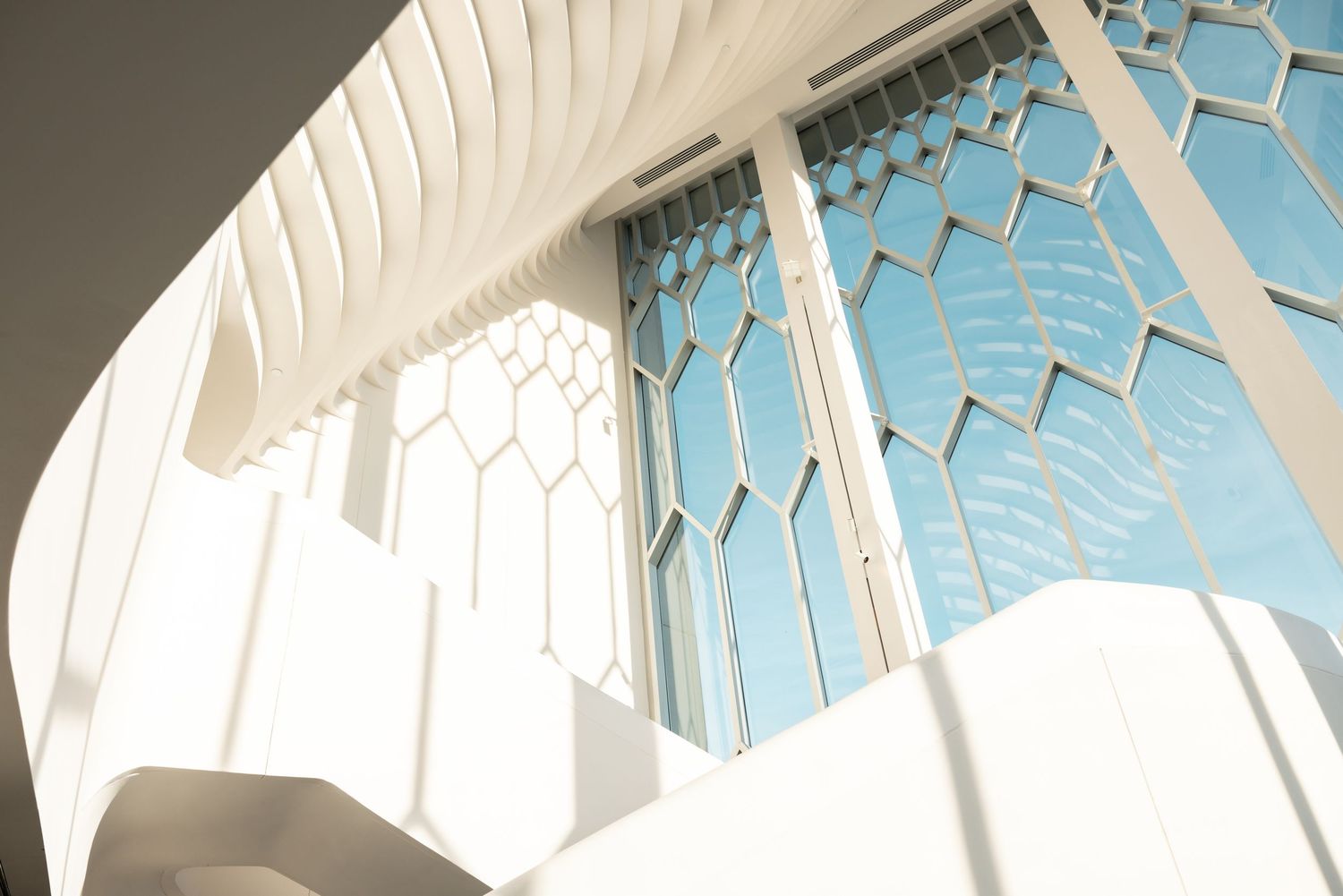 Architectural detail of a white curved building with geometric blue stained glass windows.