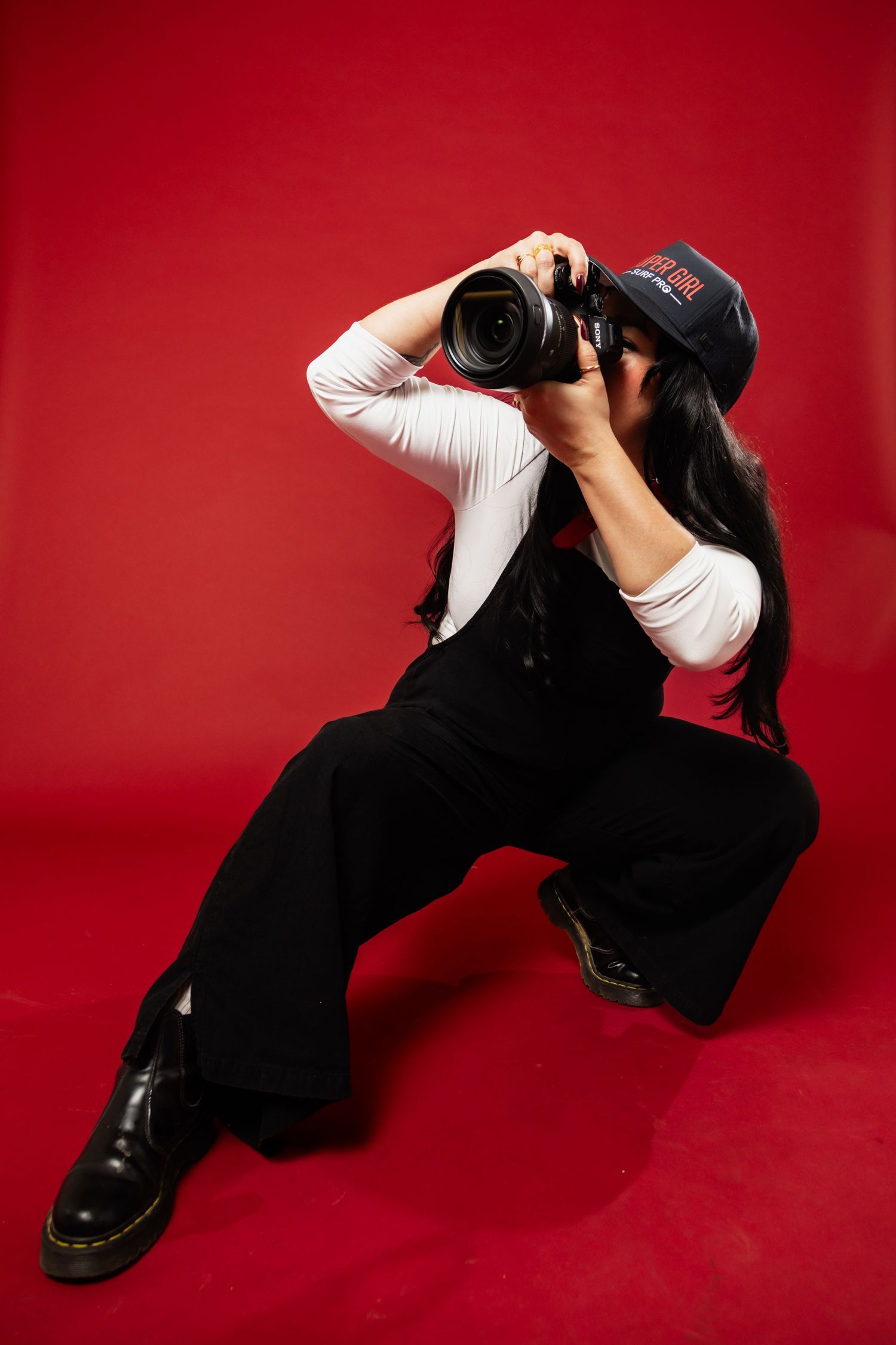 Photographer taking a photo during a shoot in a studio with a red background
