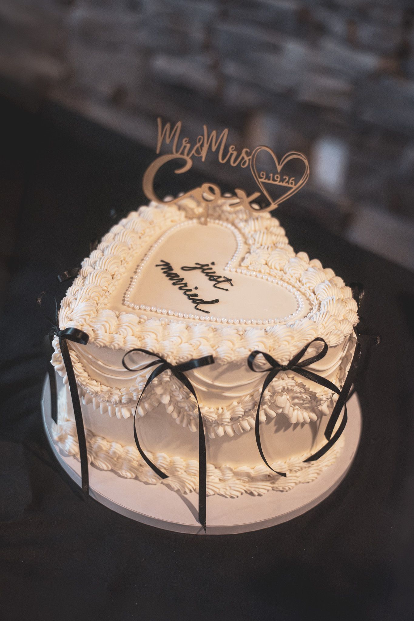 Elegant heart-shaped white wedding cake with black bows and Mr. & Mrs. topper reads just married.