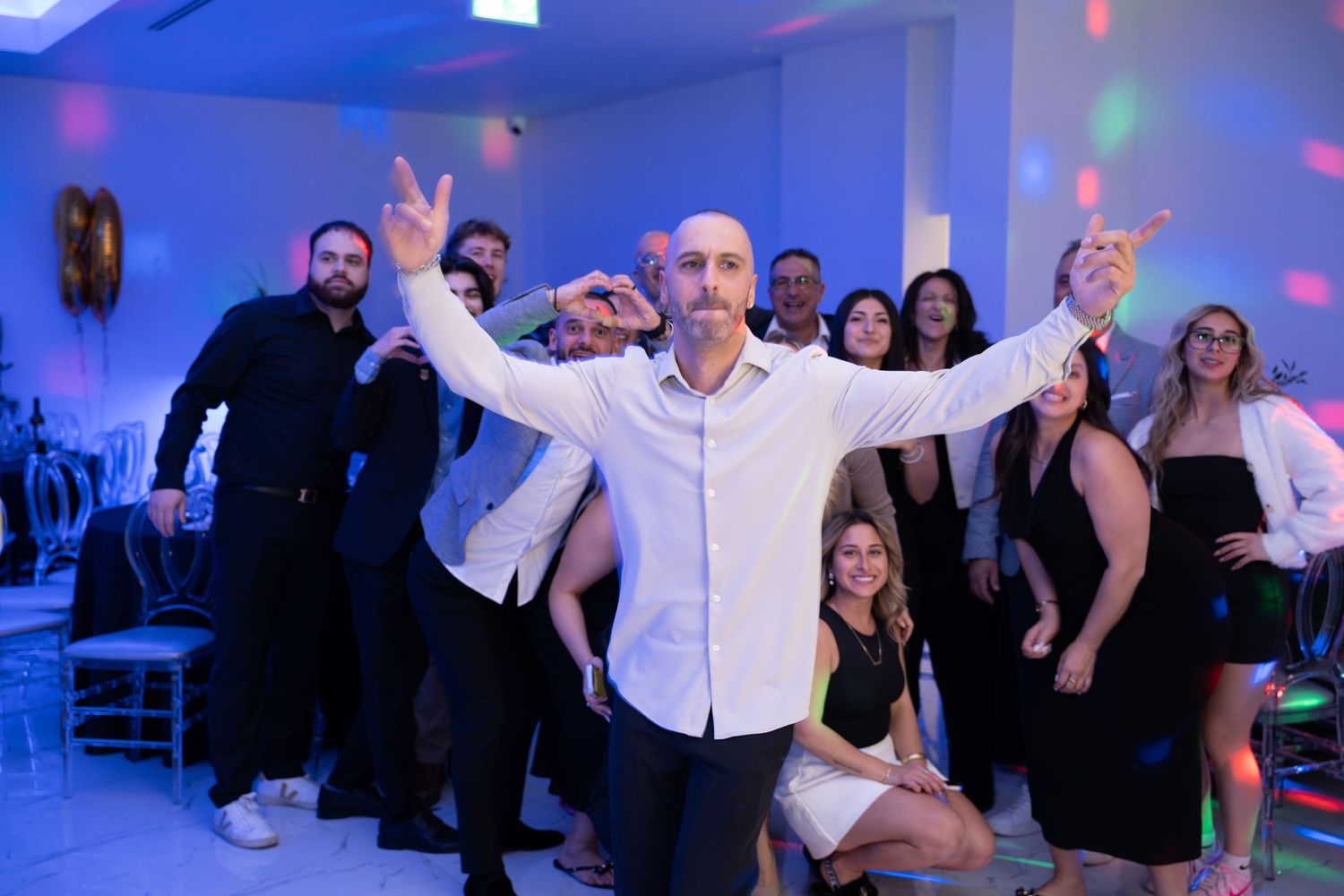 Event guests dancing and celebrating with enthusiasm under atmospheric blue lighting.
