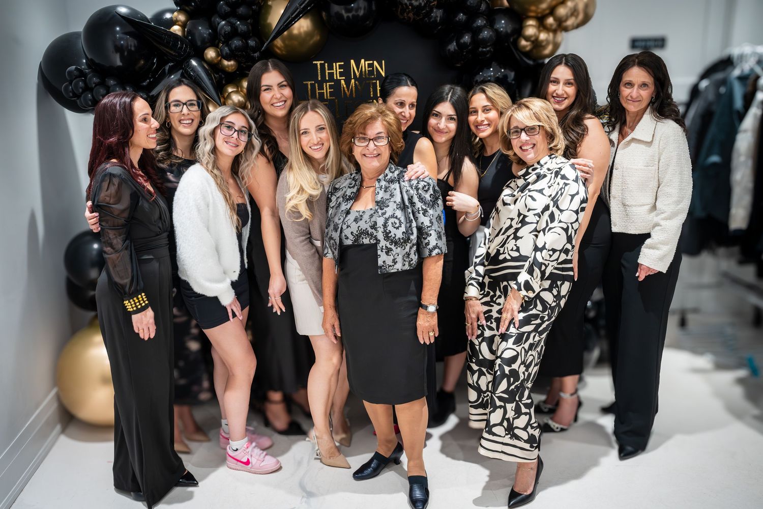 Party guests gathered for group photos with elegant black and gold party decorations.
