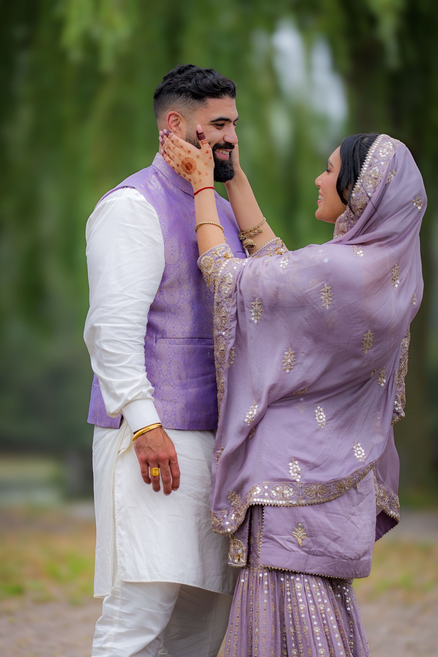 An intimate portrait of a couple in coordinated purple outfits sharing a tender moment outdoors.