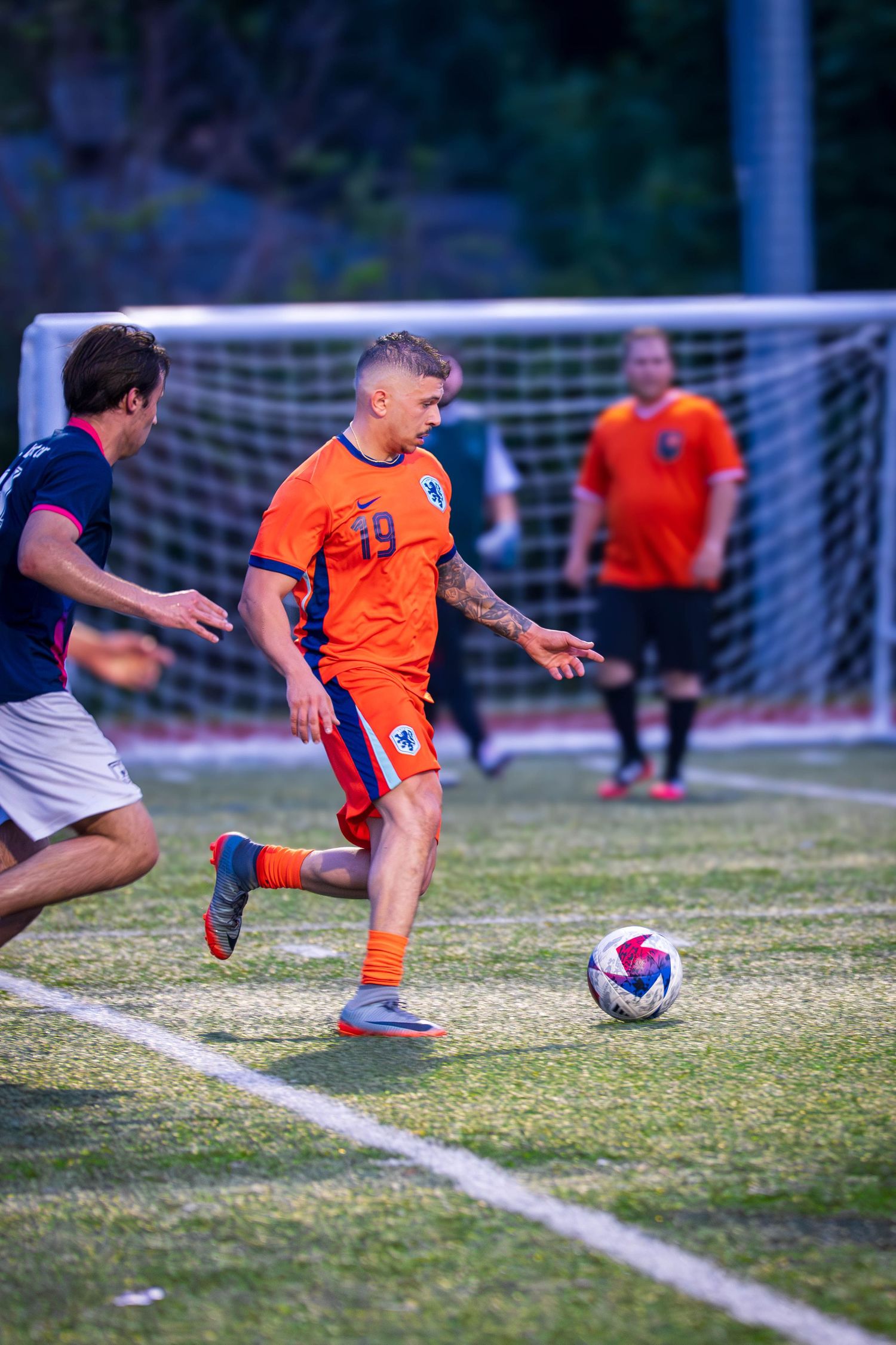 Soccer player in orange jersey attempts to control ball during game action.