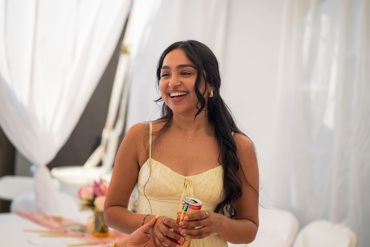 A guest in yellow dress laughs during a baby shower celebration.