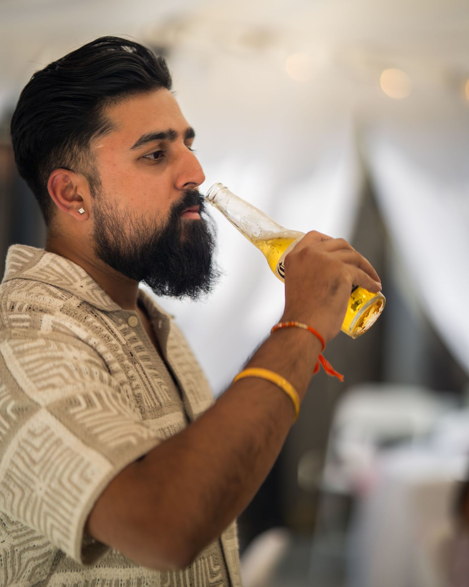 Person in patterned shirt enjoying a beverage at an indoor event.