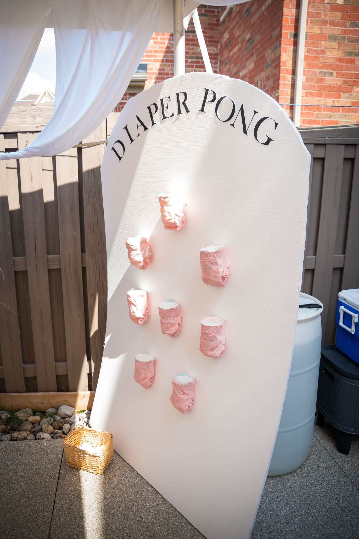 Paper pong game setup with pink cups against a white backdrop at a party.