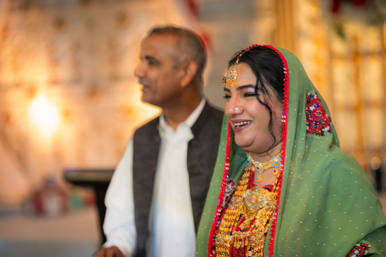 Wedding celebration with traditional attire and decorative floral arrangements in warm lighting.