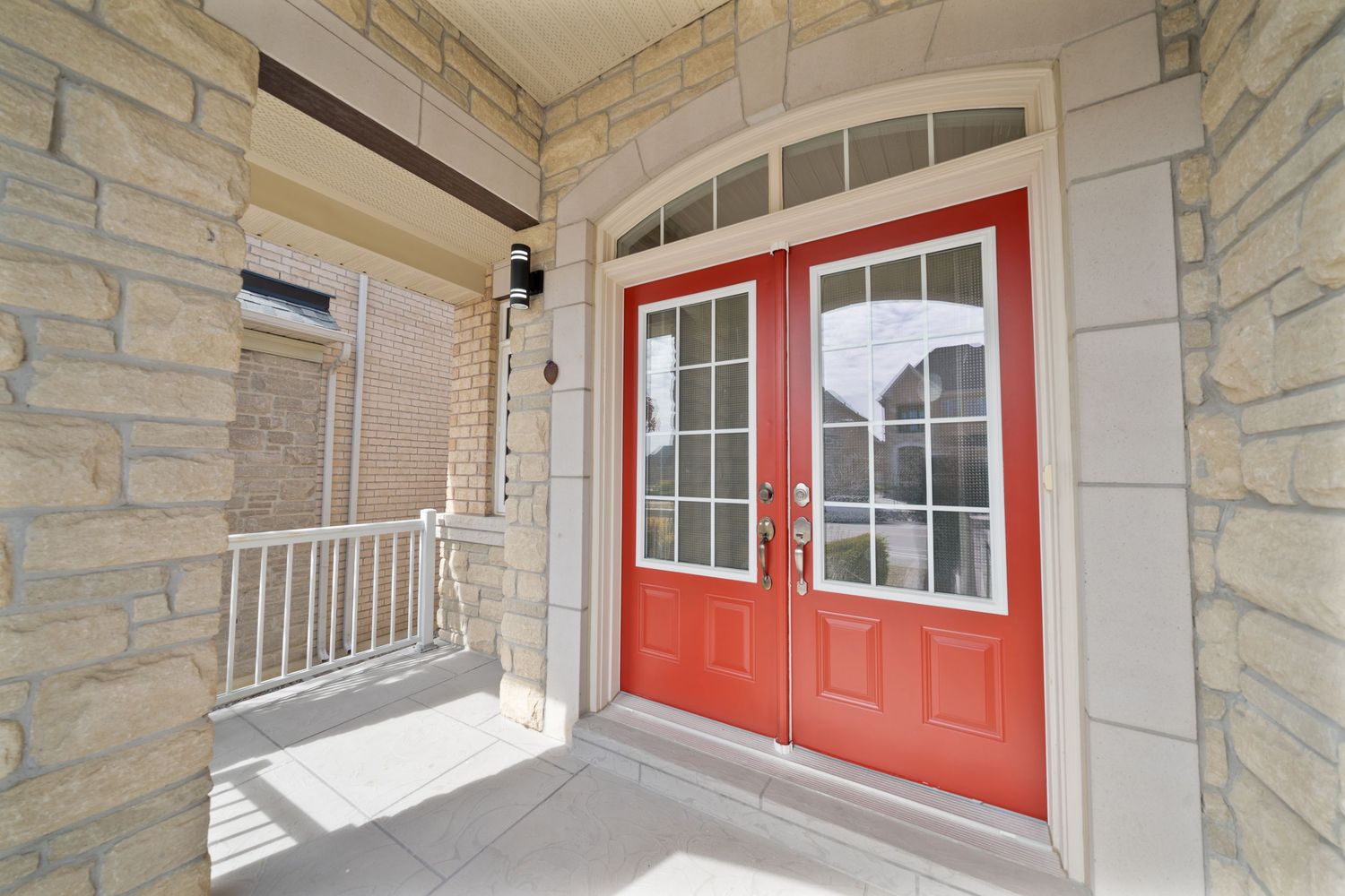 Modern townhouse exterior features a red front door and stone facade with large windows and covered entry porch.