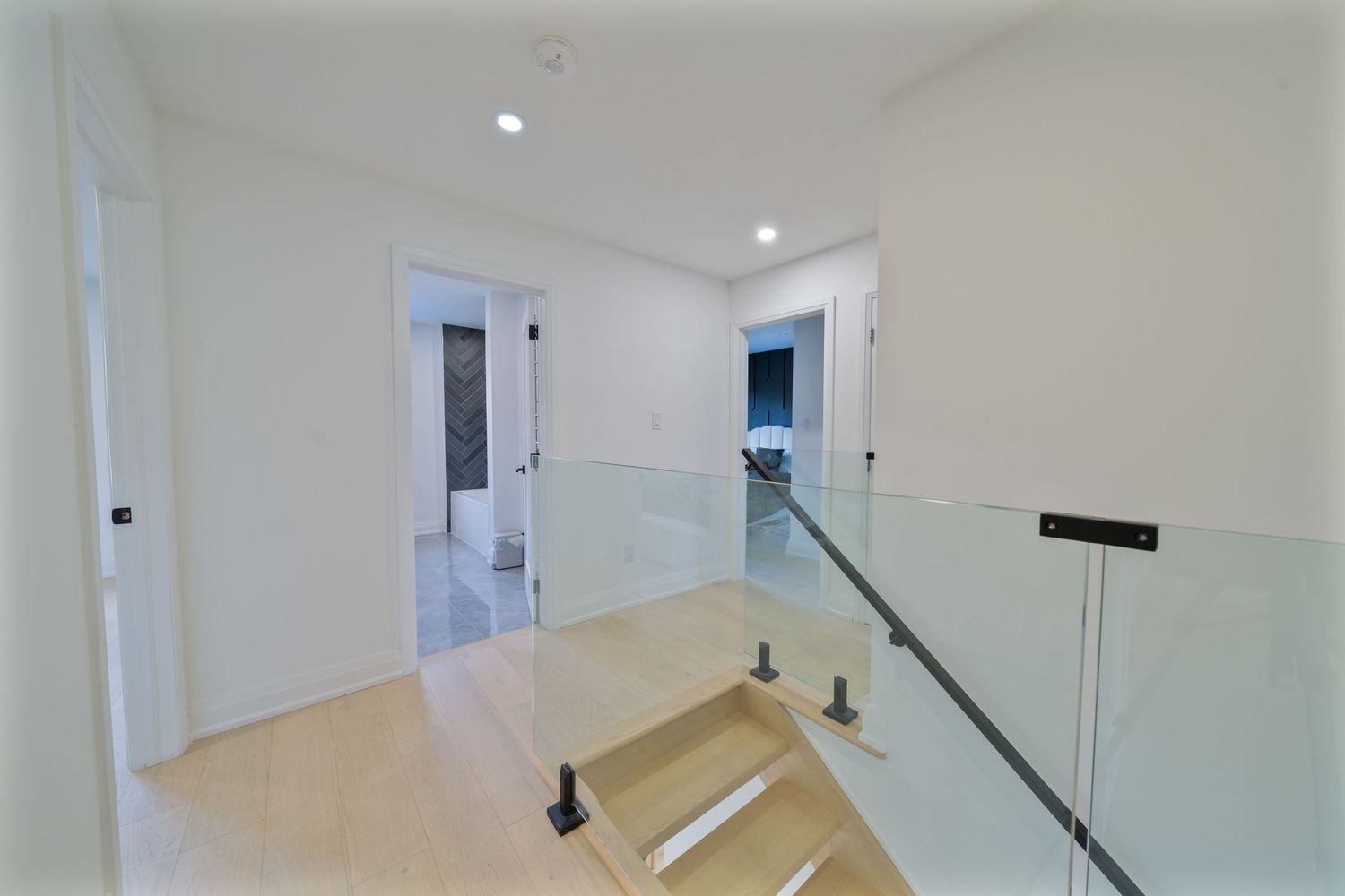 White interior hallway with glossy floors and multiple doorways leading to different rooms.