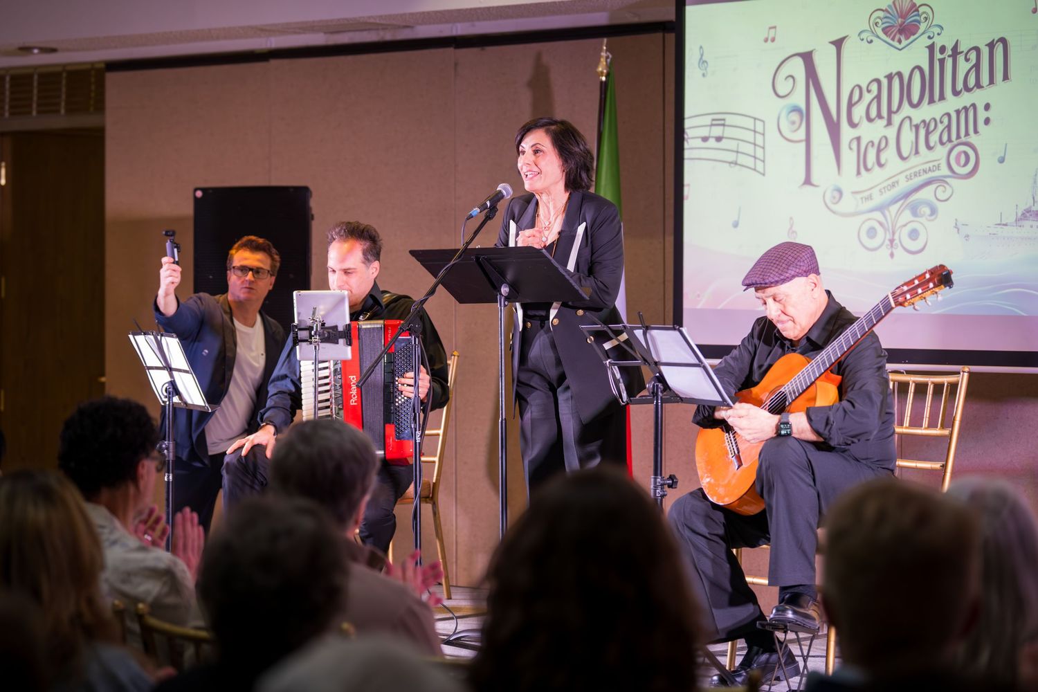 Four musicians perform on stage at a Neapolitan Ice Cream show, featuring accordion, guitar, and vocals.