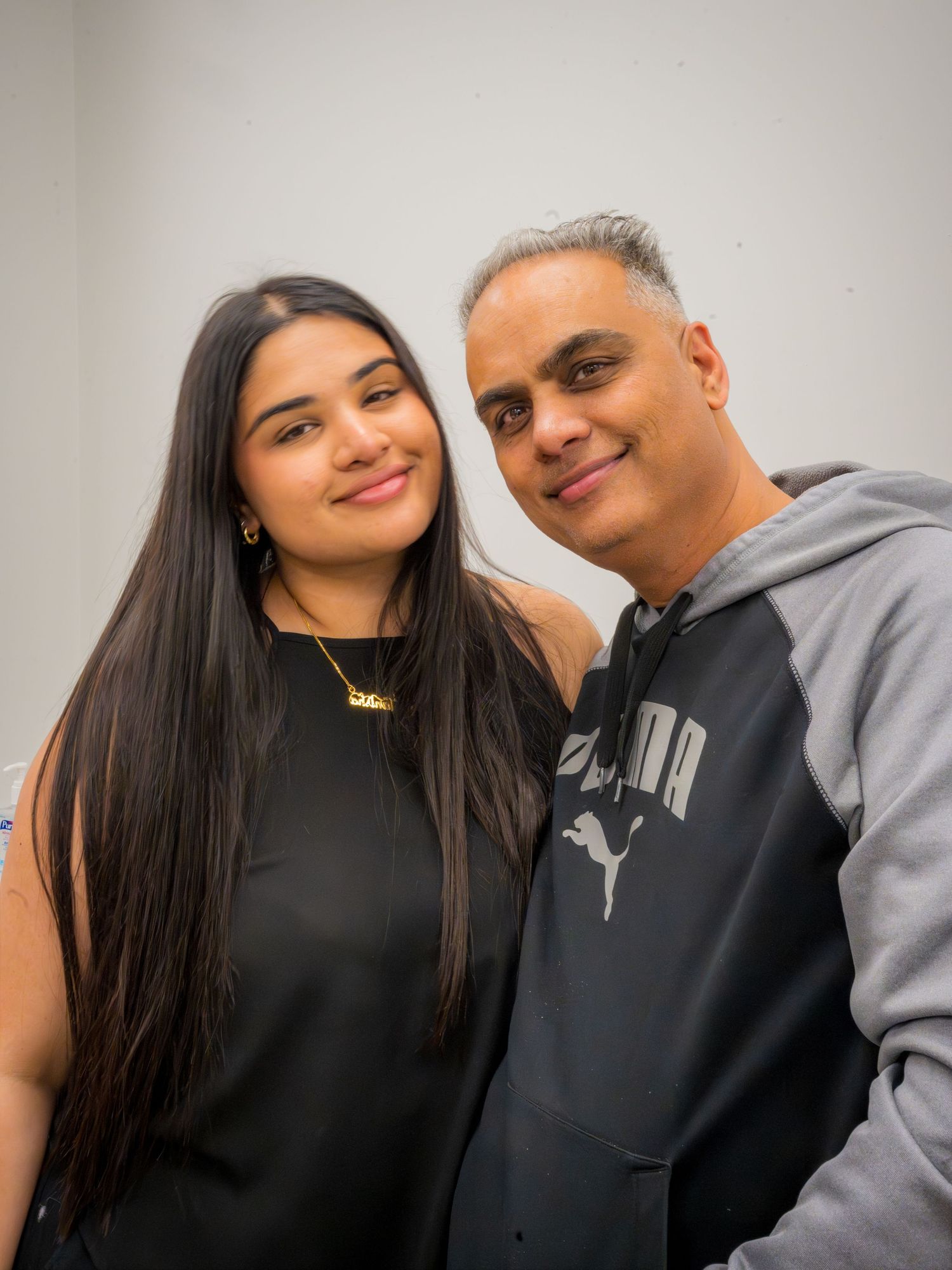 A young woman and older man with gray hair smile together for a portrait photo.